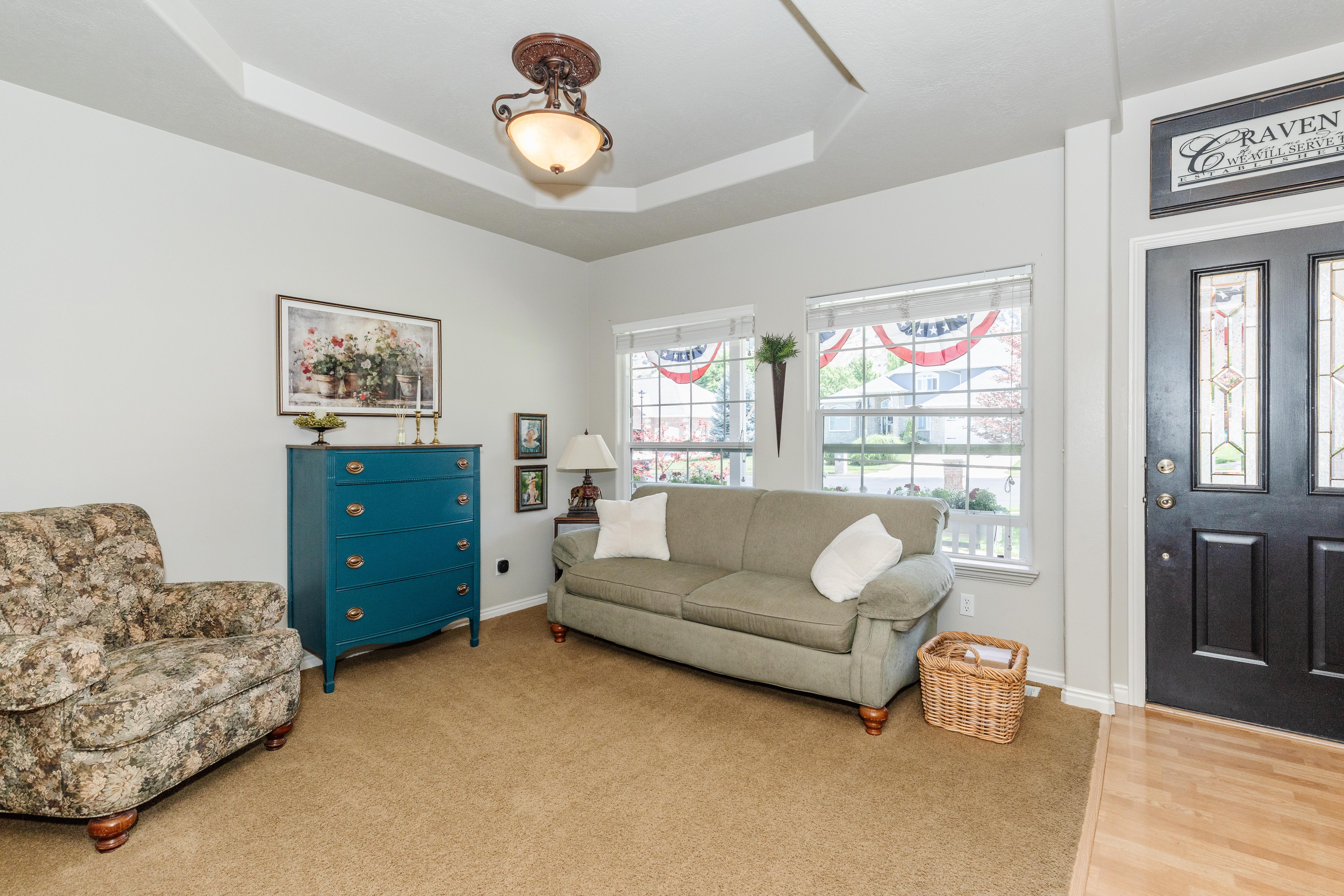 Tray ceiling with decorative light fixture, complemented by light-colored walls and carpeted flooring