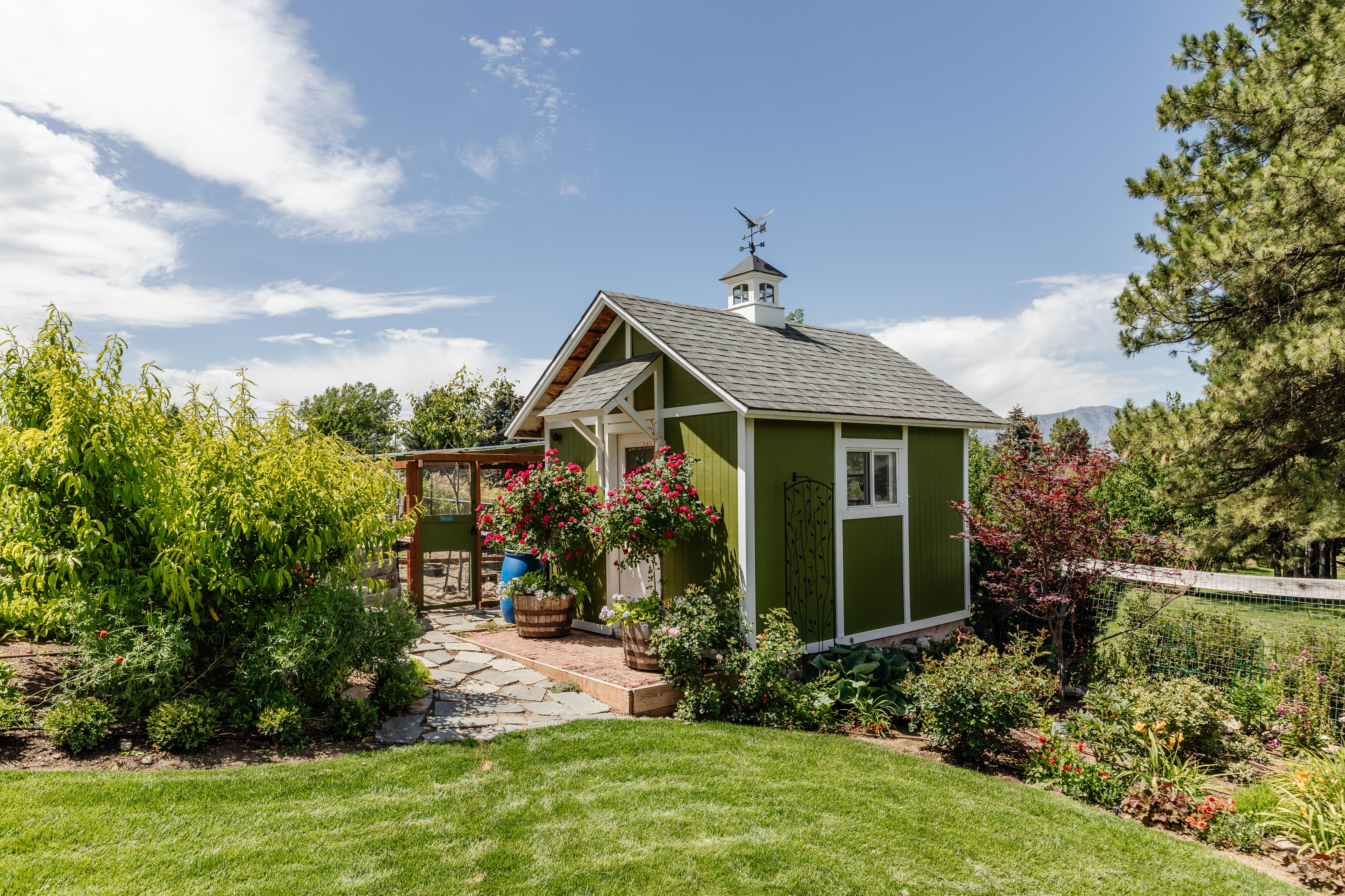 Green outbuilding with white trim details and a cupola with a weathervane