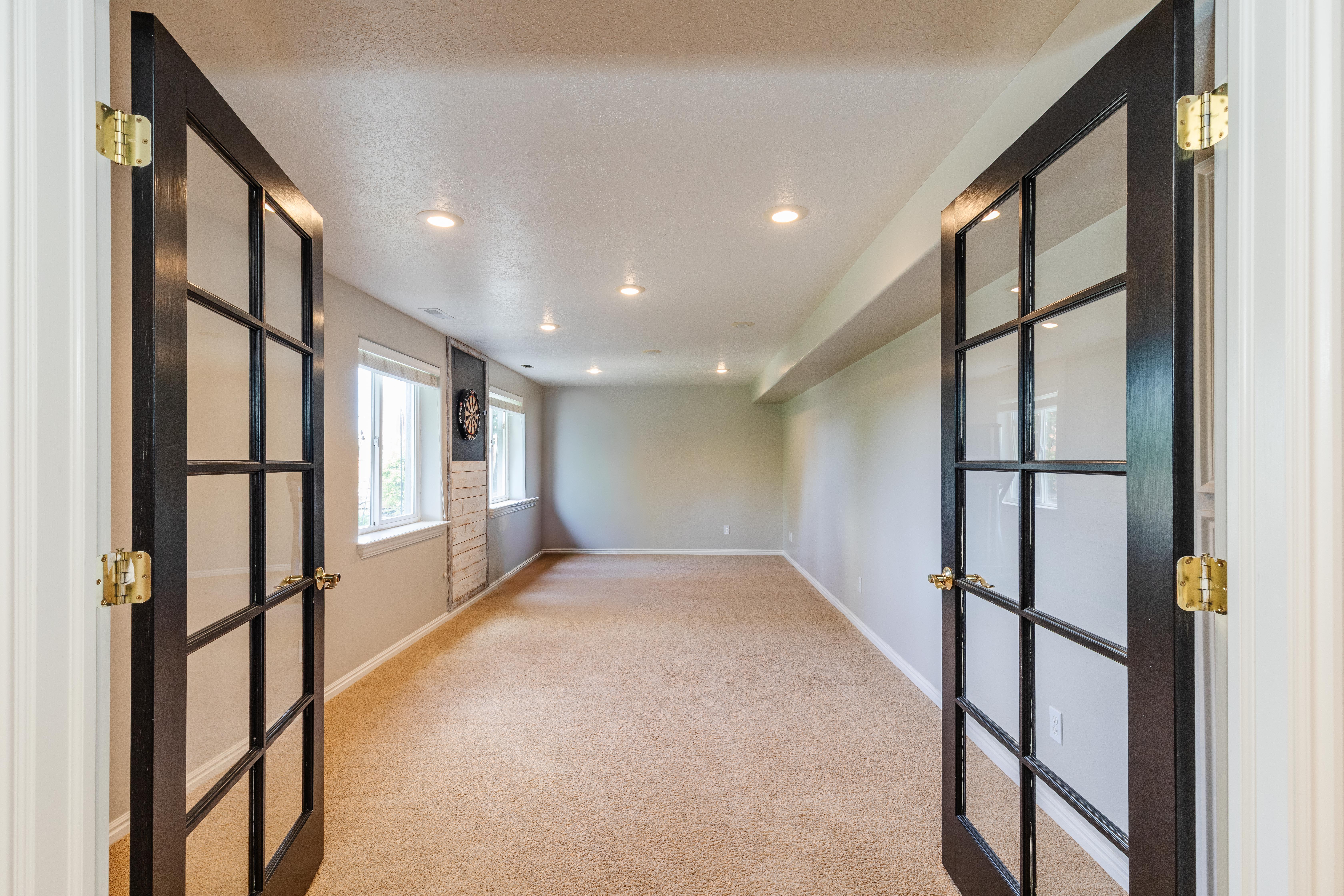 Spacious room featuring French doors, recessed lighting, multiple windows, and light brown carpeting