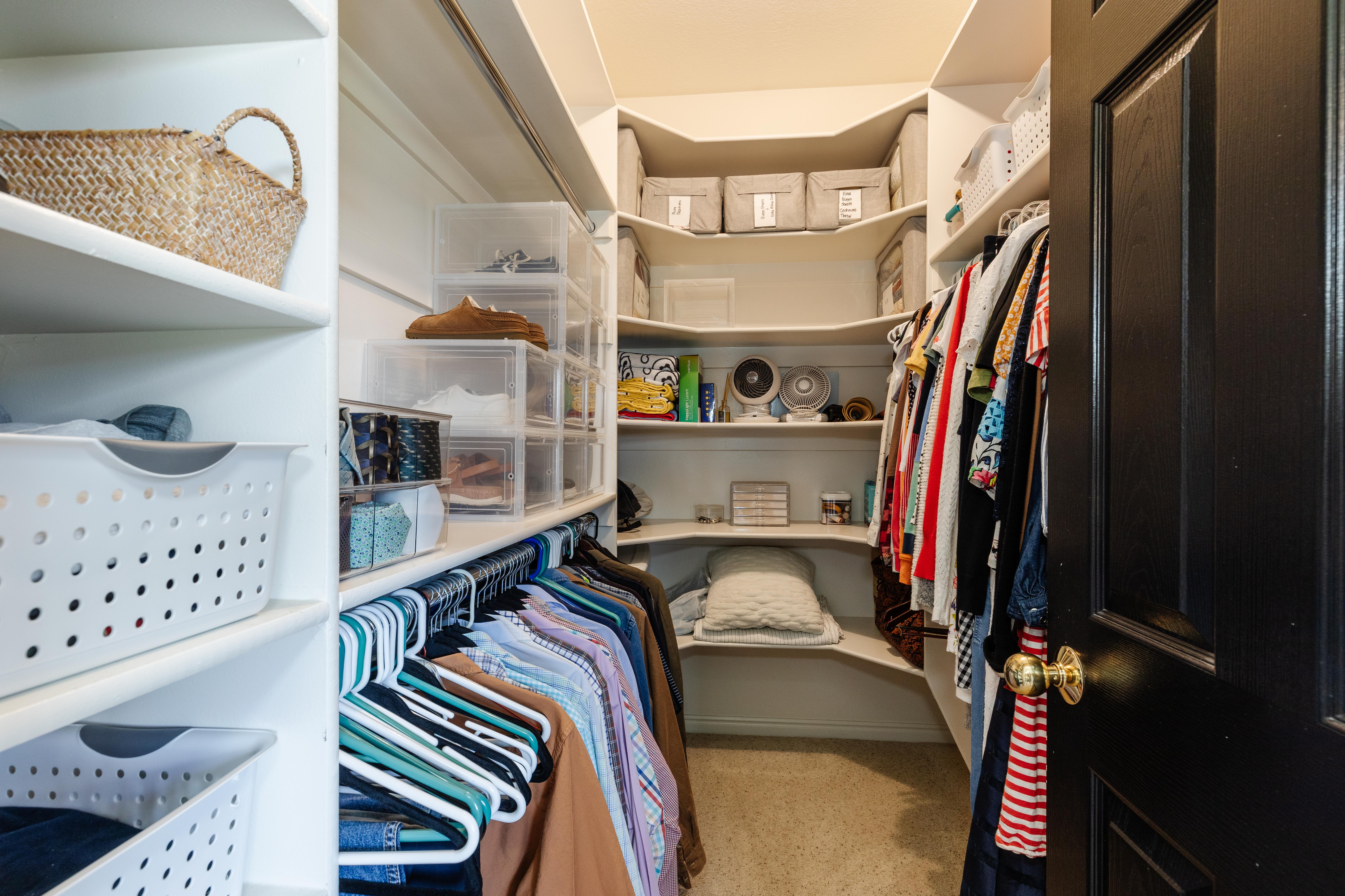 Walk-in closet featuring built-in shelving, hanging rods, corner shelving, and carpet flooring