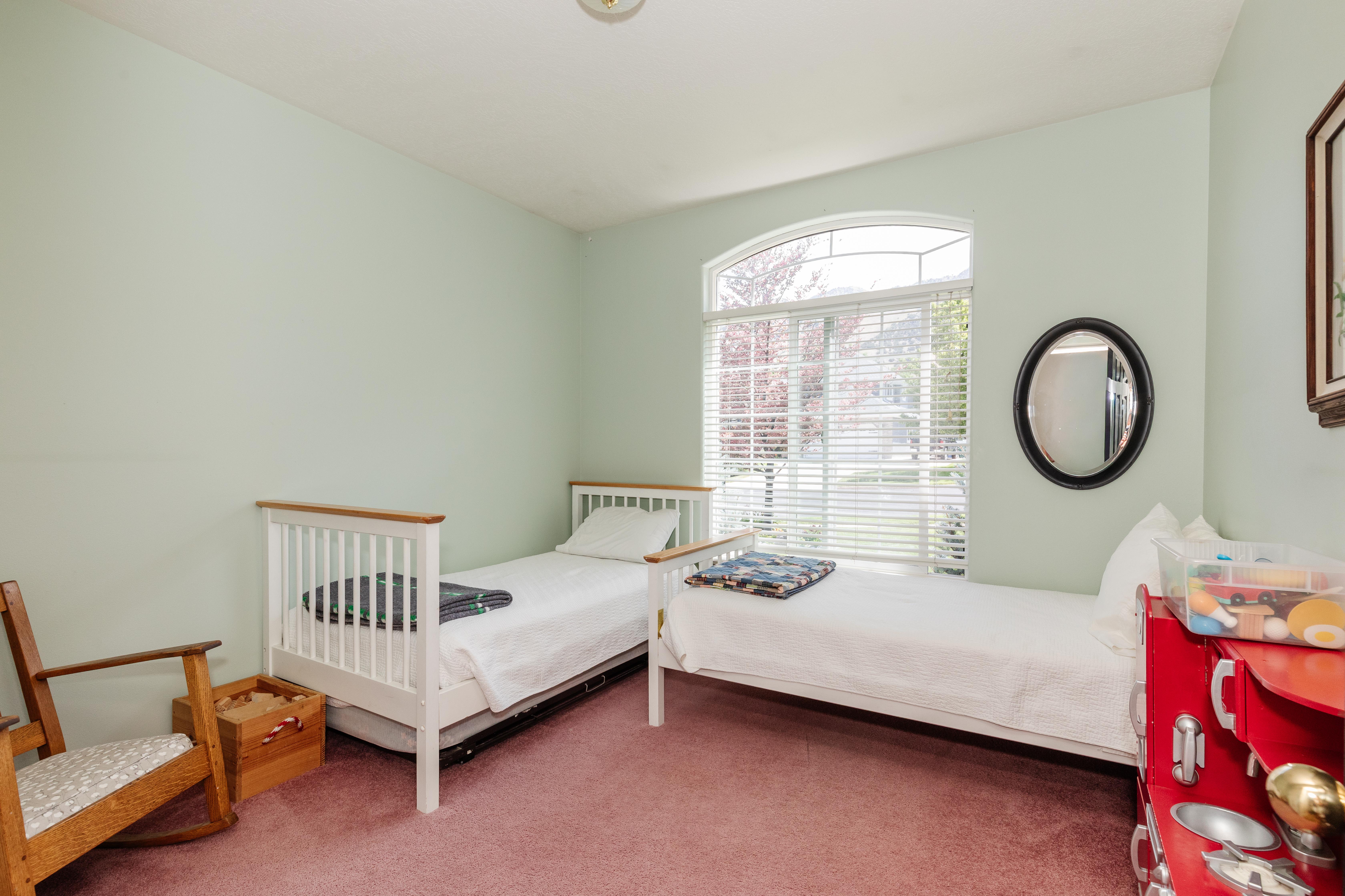 Interior room featuring a large arched window with blinds, light green walls, and pink carpeting