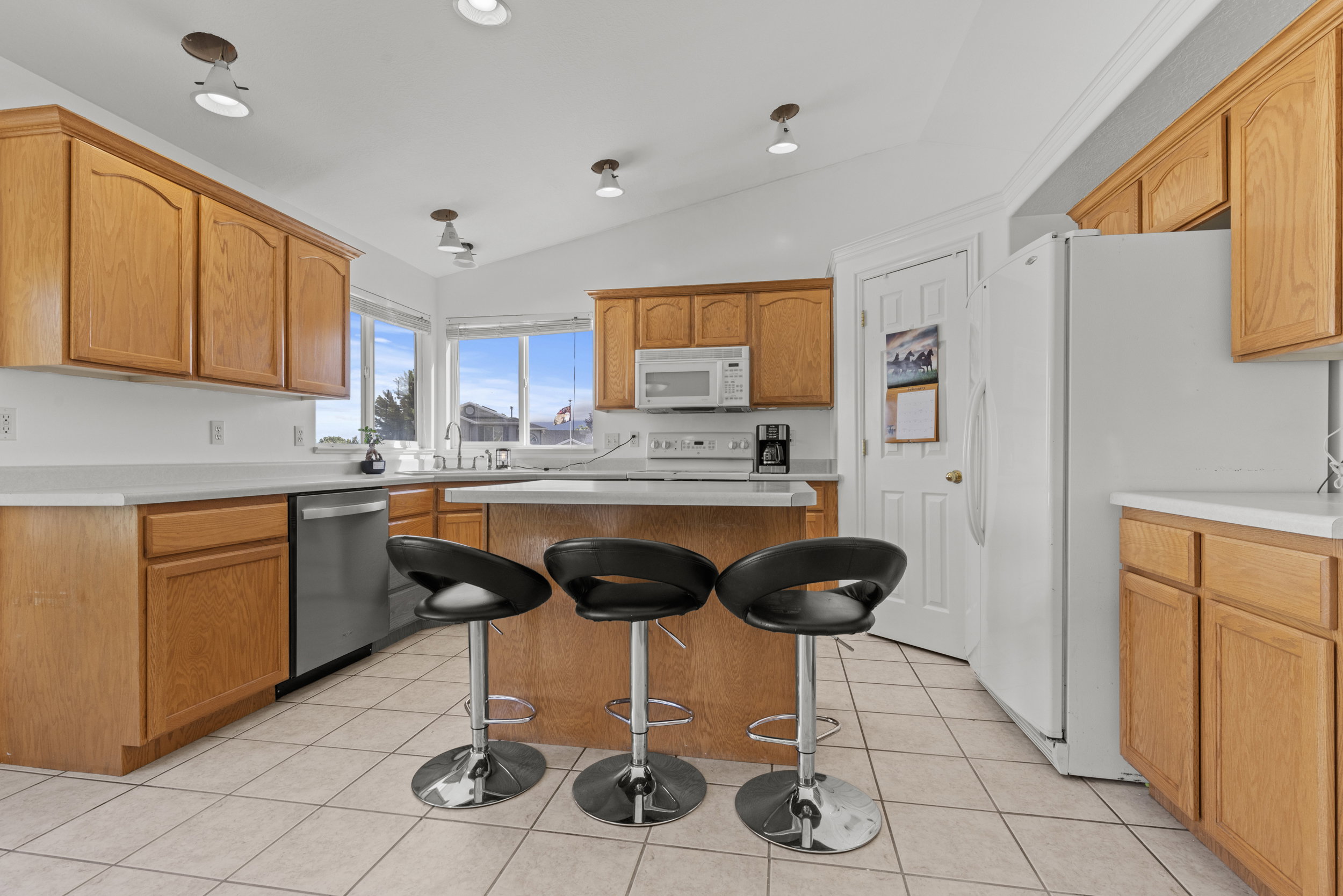 Spacious kitchen featuring wood cabinetry, light-toned countertops, and a central island with bar seating