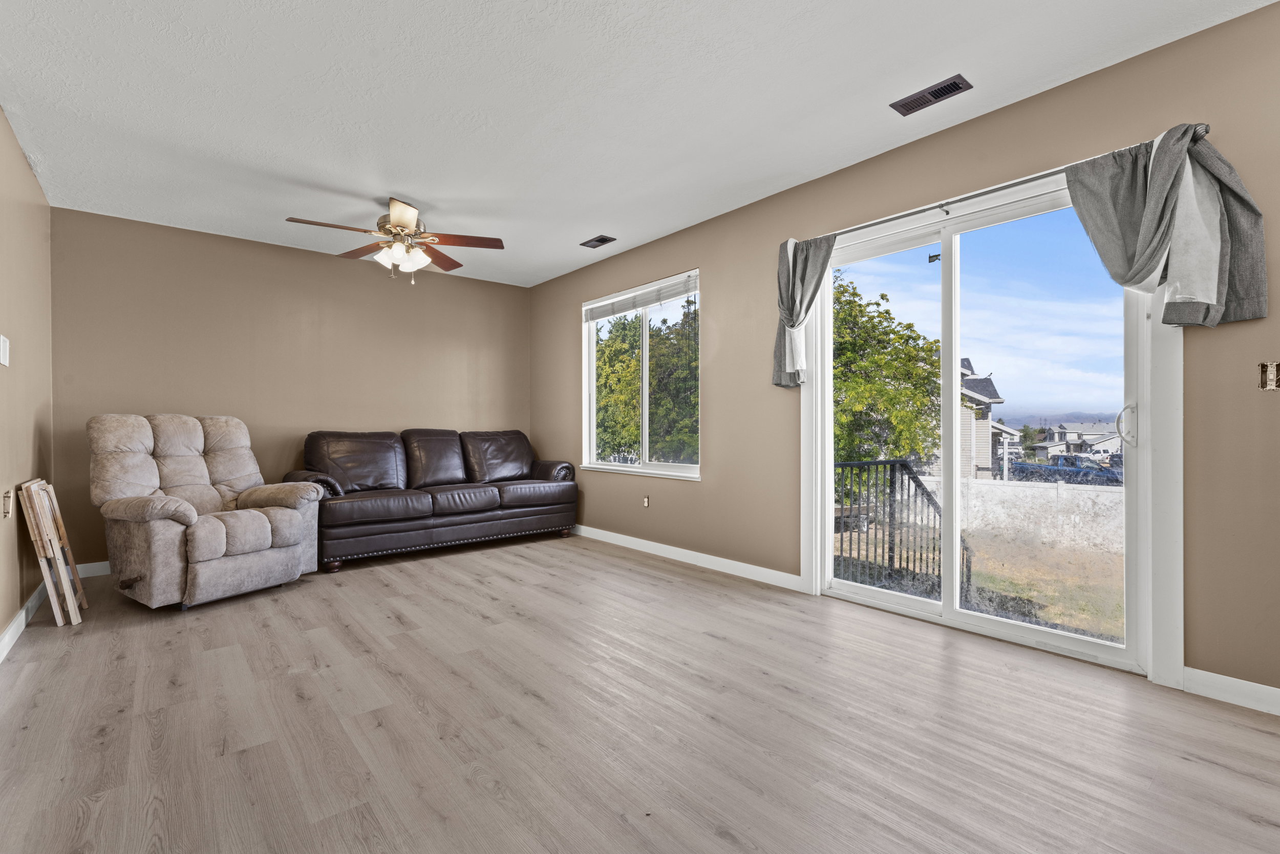 Spacious living area featuring light wood-finish flooring, neutral wall paint, and a white ceiling