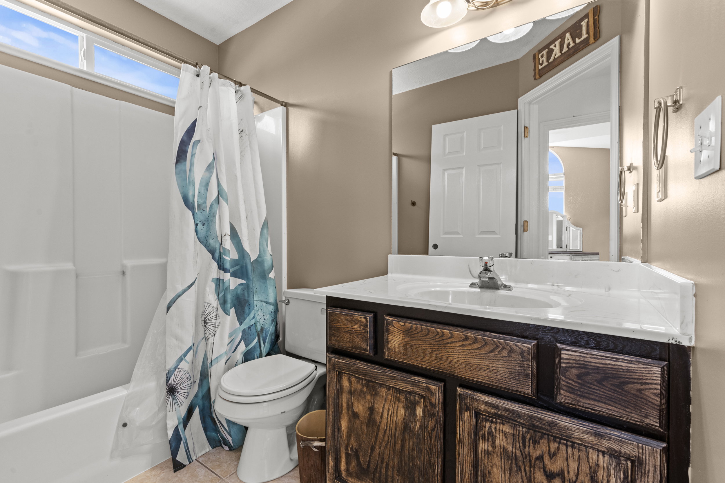 Bathroom featuring a white bathtub and shower surround, a toilet, and a vanity with a white countertop