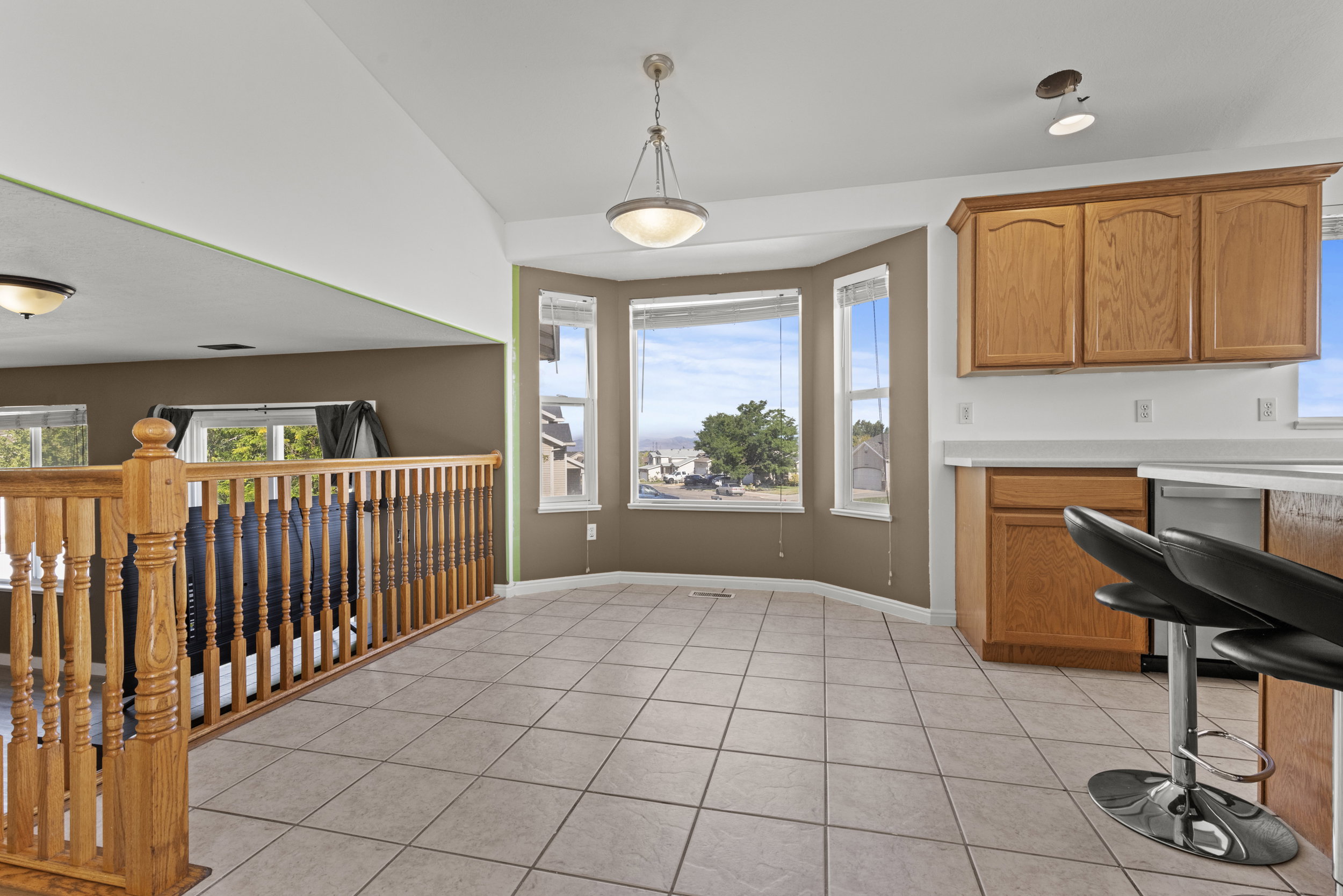 Bay window dining area featuring tile flooring, a contemporary pendant light fixture, wood cabinetry, and white countertops