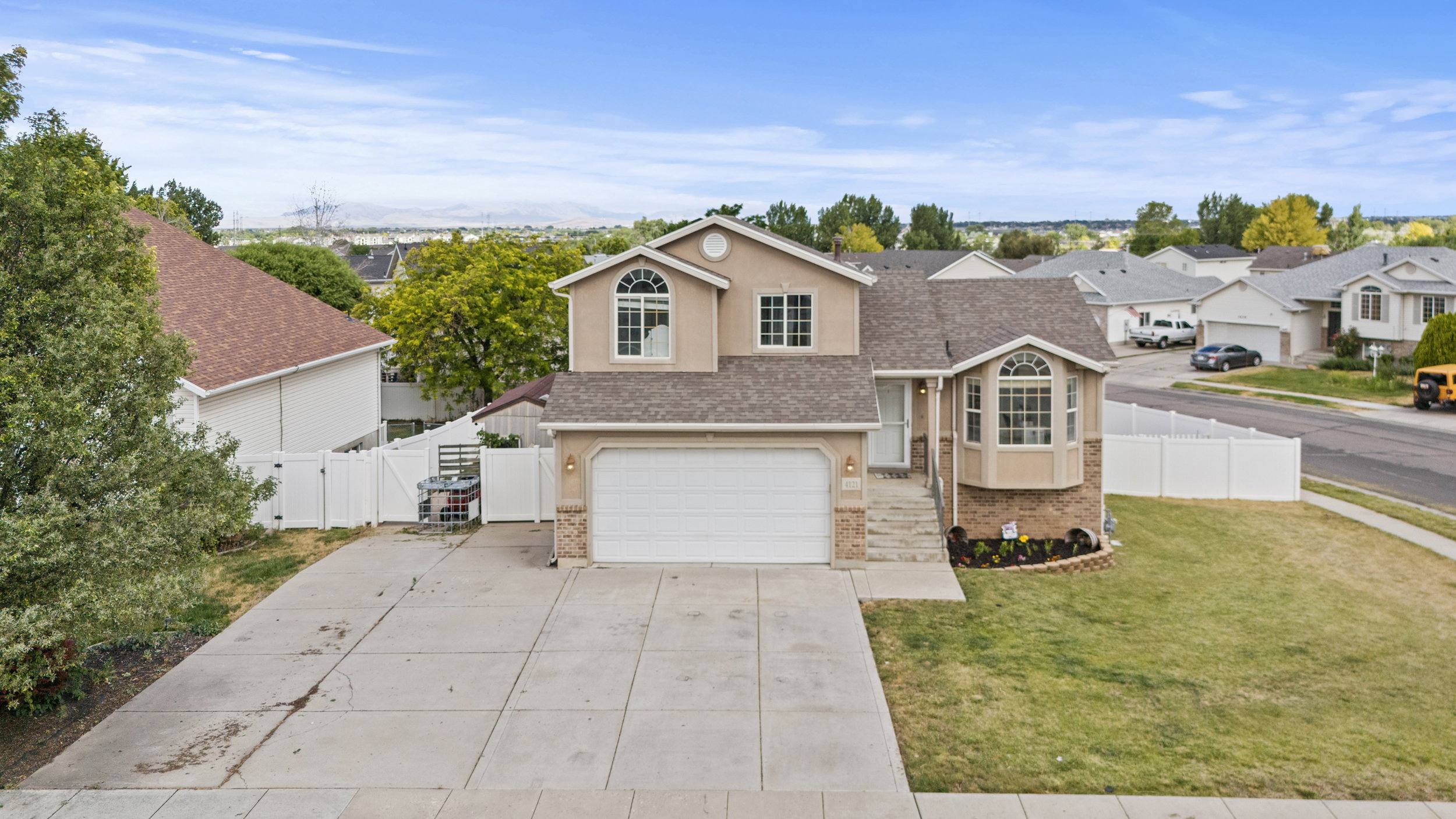 Two-story residential property featuring a neutral stucco exterior with stone accents, a two-car garage, and a large concrete driveway