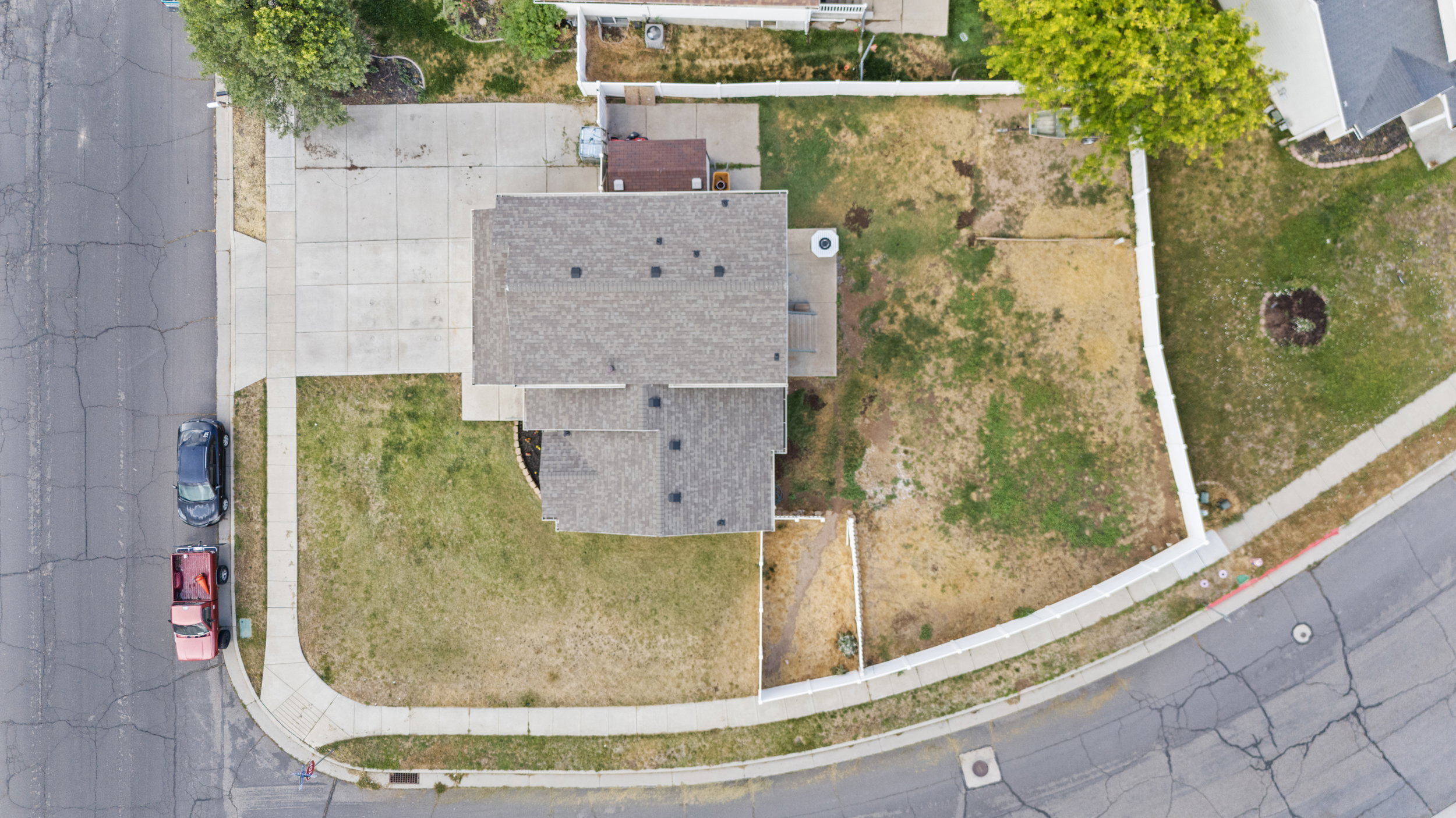 Corner lot property featuring a shingled roof, concrete driveway, and established sidewalks