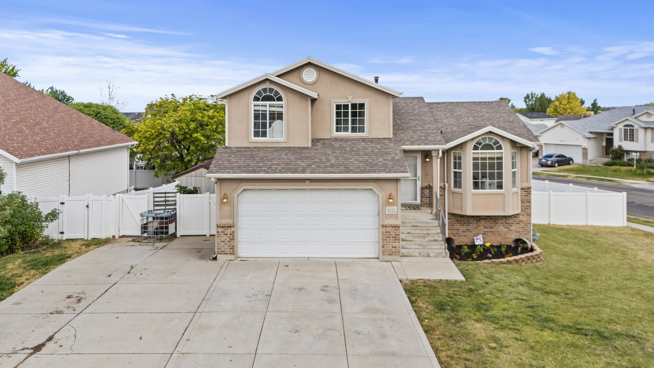 Two-story residence featuring a stucco exterior with brick accents, a prominent front bay window, an attached two-car garage, and a concrete driveway