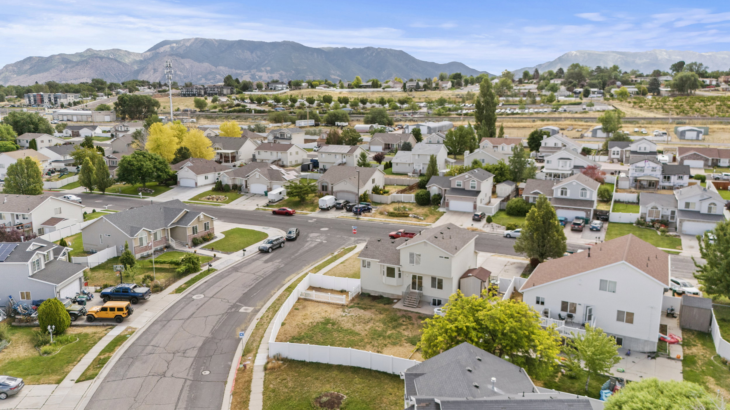 Residential neighborhood featuring a mix of single-family homes, paved streets, and mountainous terrain in the distance