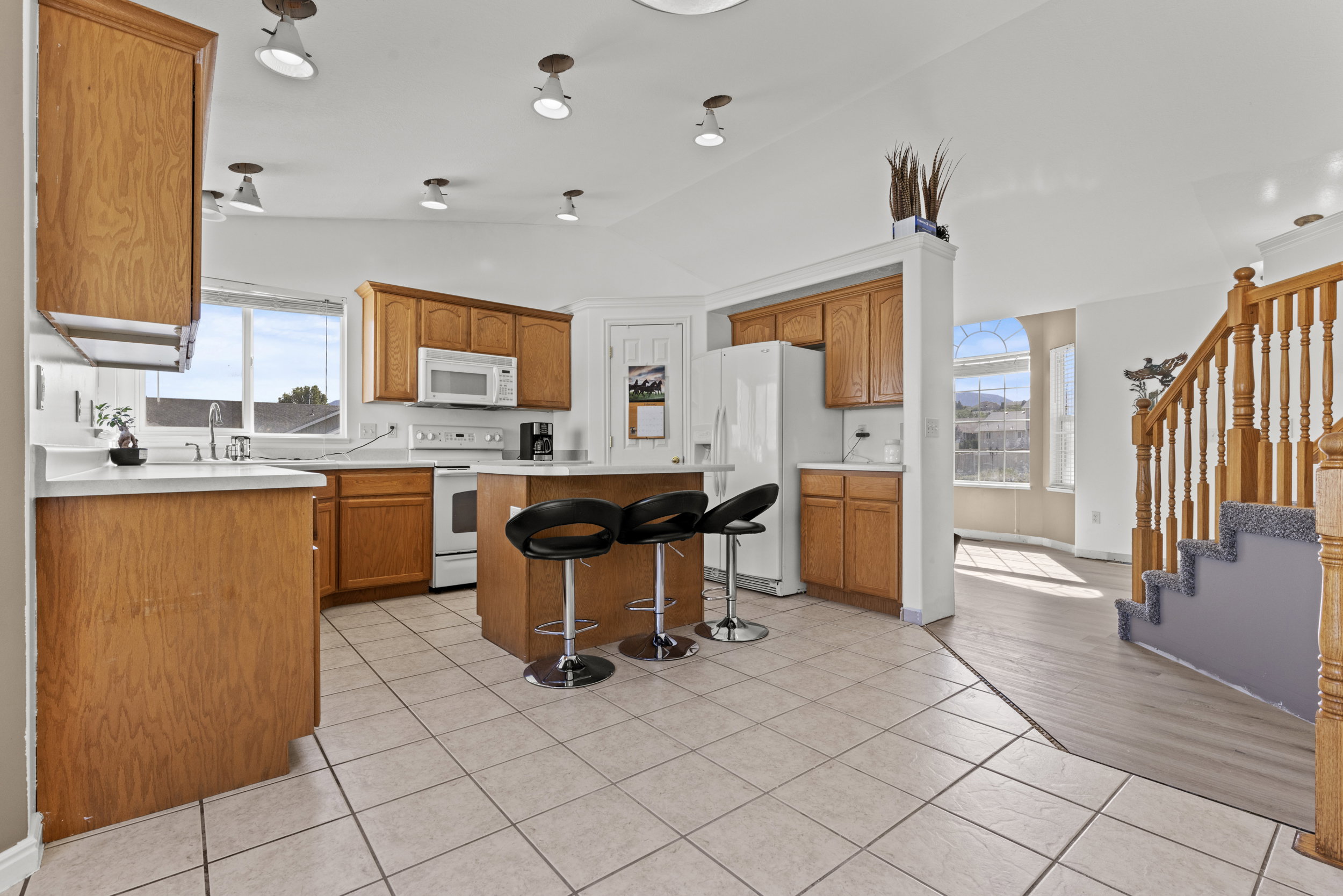 Kitchen featuring wood cabinetry, white countertops, built-in appliances, a central island with seating, and tile flooring