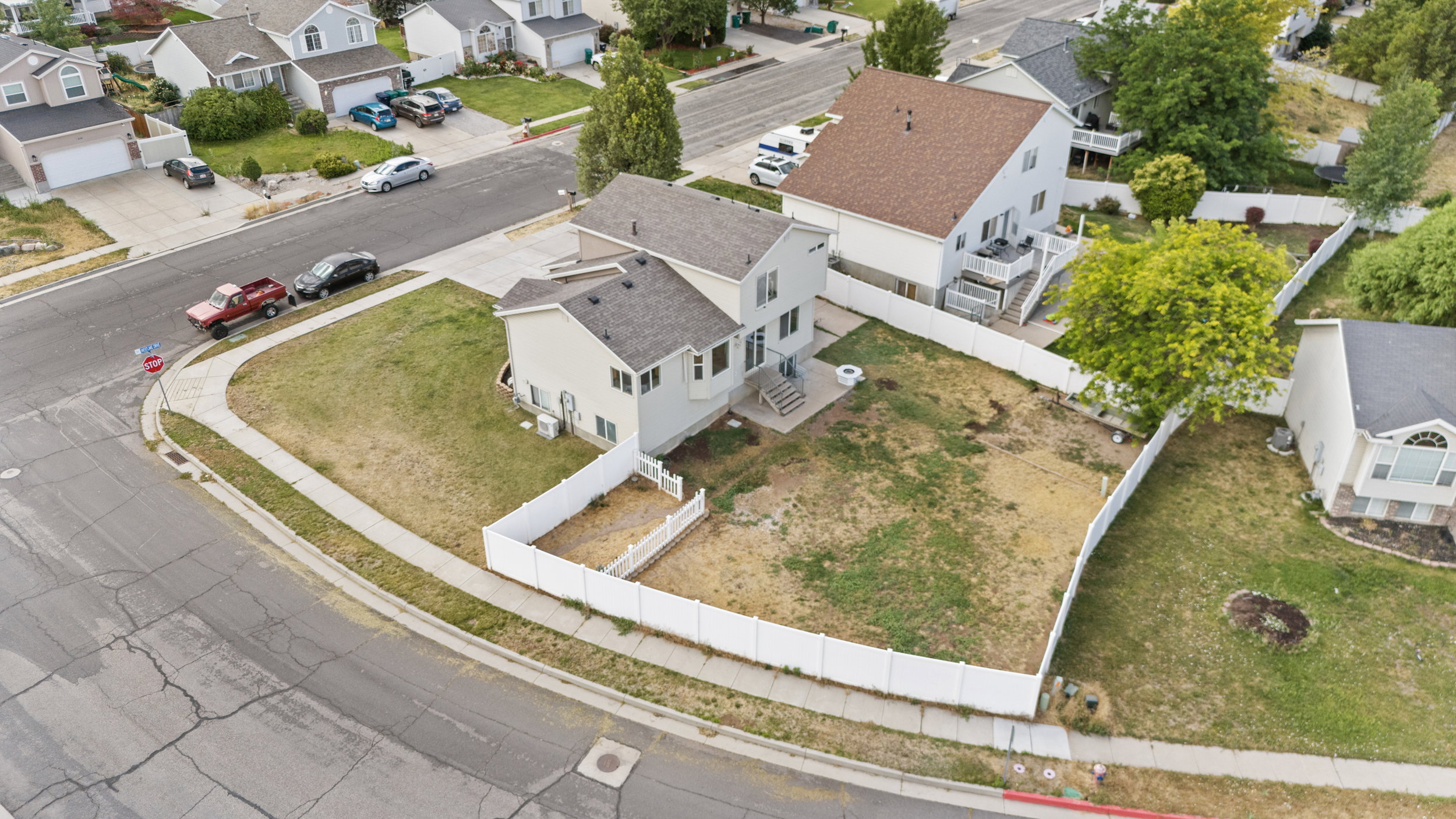 Corner lot residence featuring a two-story design, light-colored siding, and a dark shingle roof