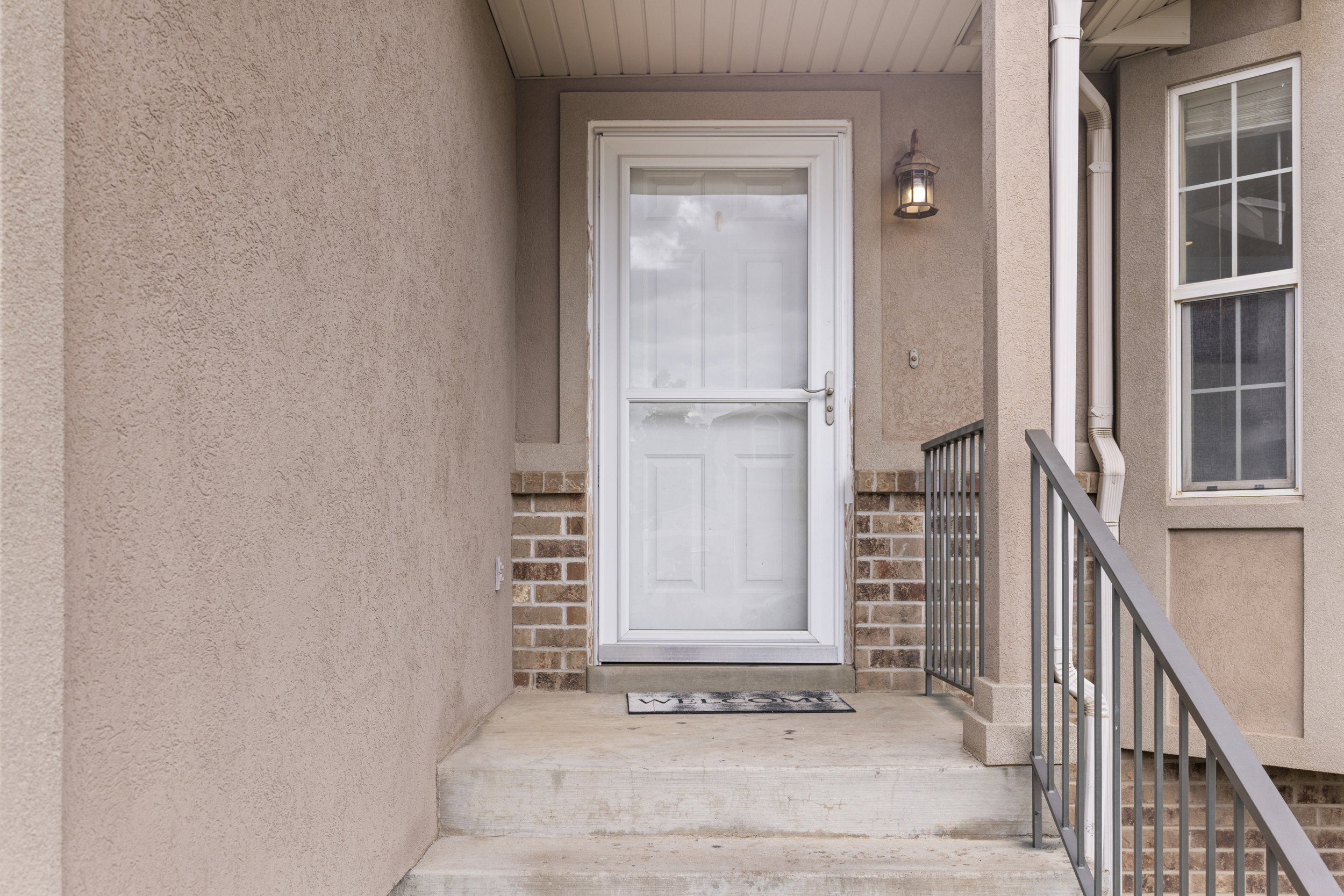 Entryway featuring a white storm door, concrete steps, and a decorative outdoor light fixture