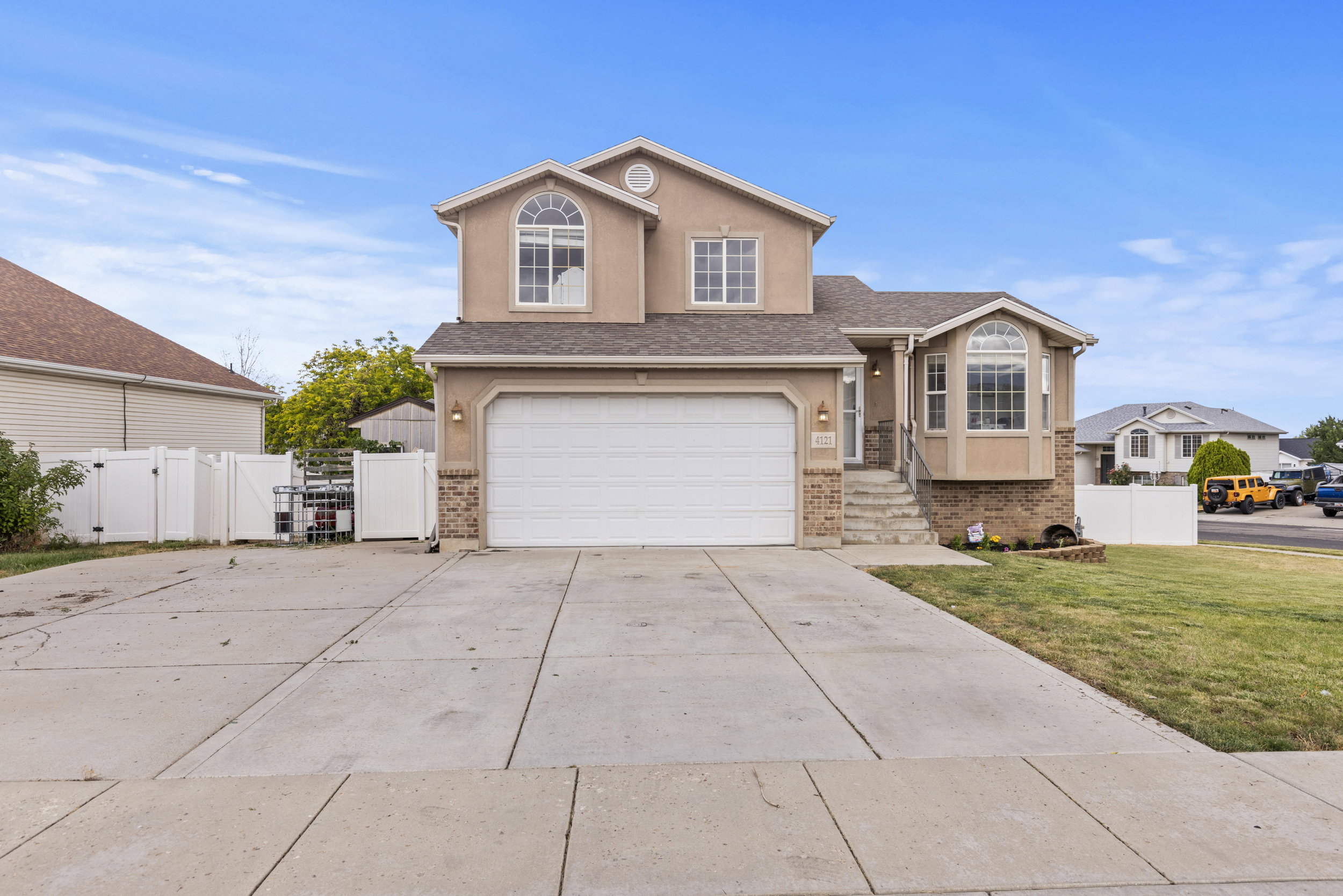 Two-story stucco exterior featuring a two-car garage, bay window, and arched window details