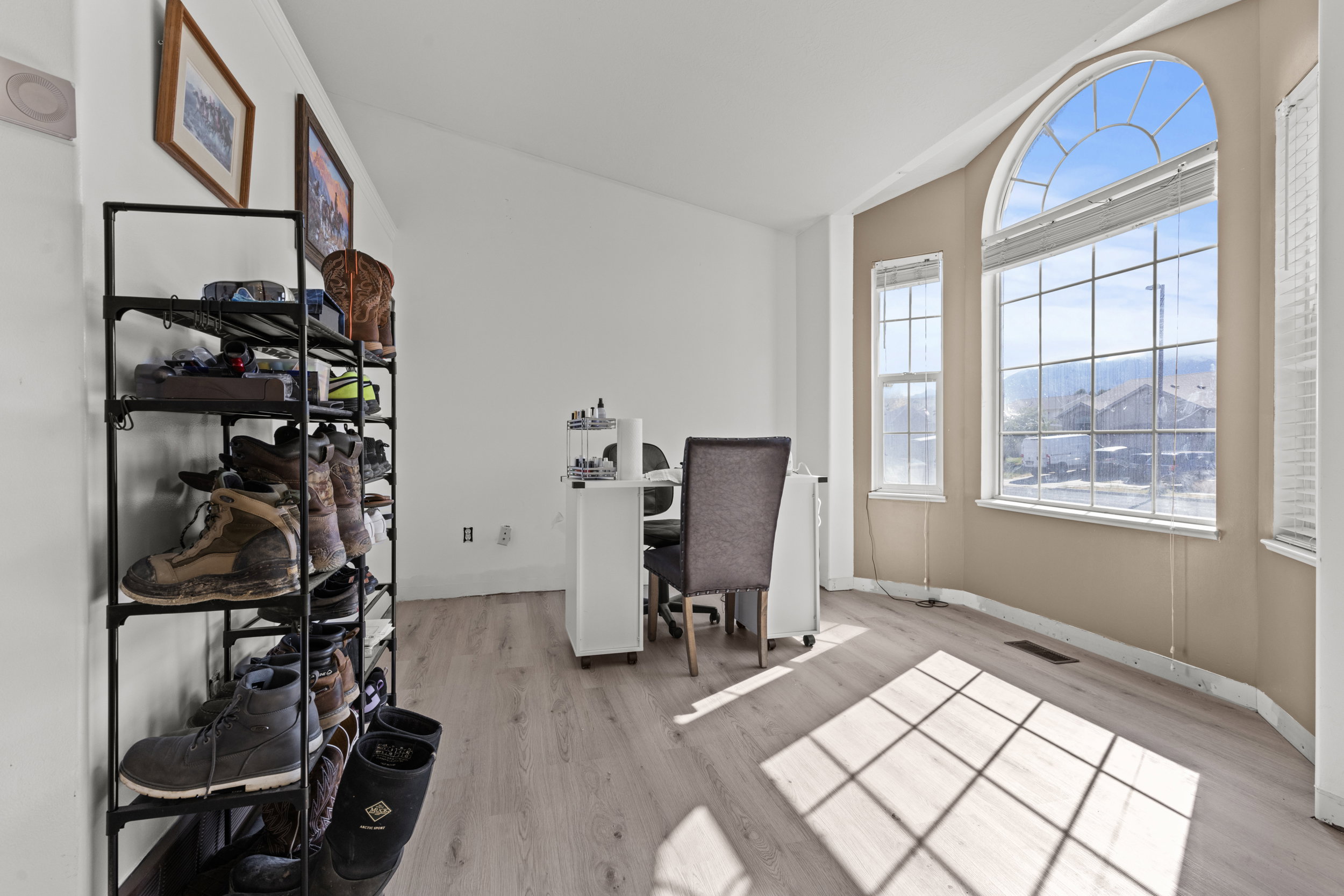 Bright interior space featuring a large arched window, a rectangular window with blinds, and light wood-finish flooring