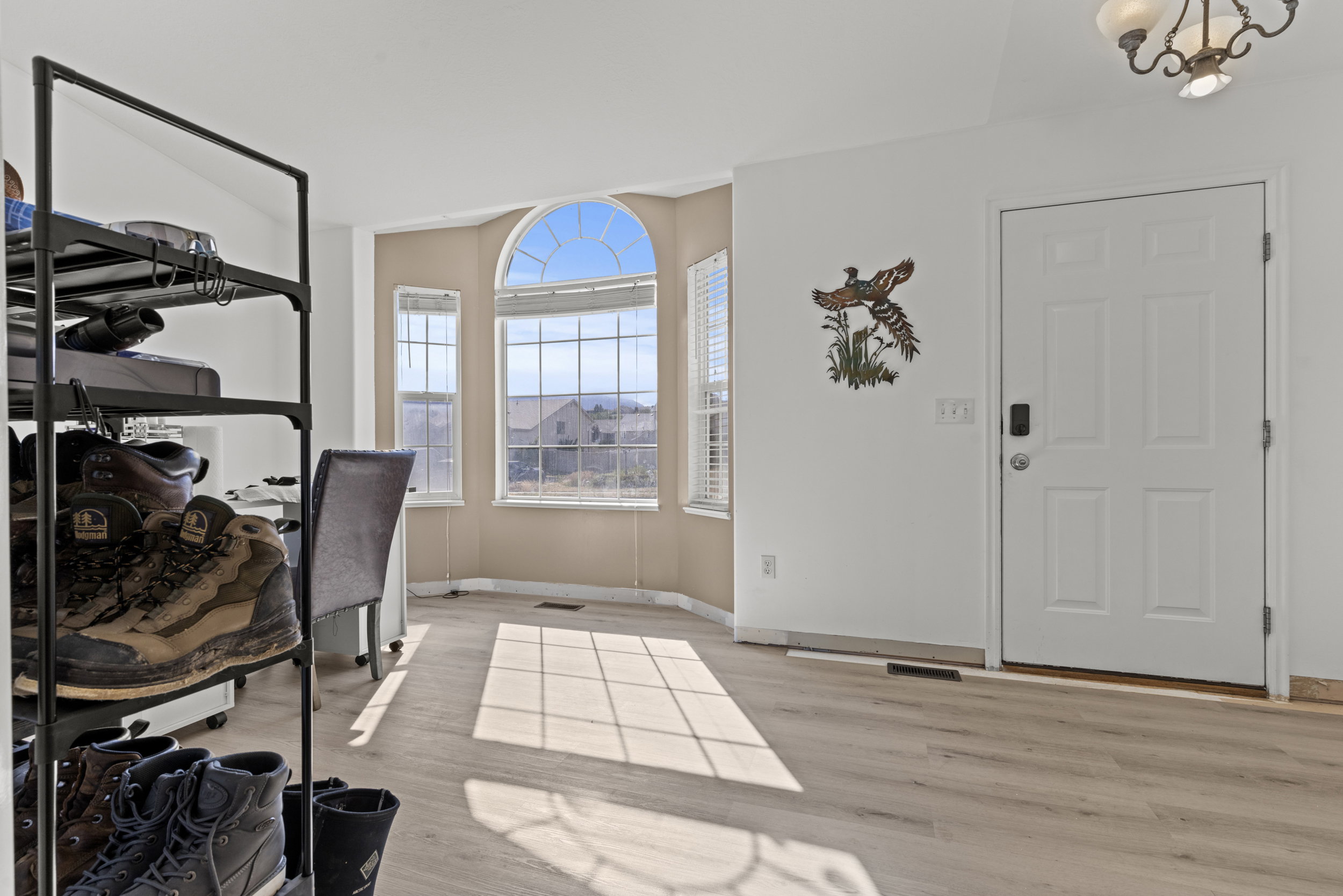 Bay window with arch transom, light wood-finish flooring, and a white paneled entry door