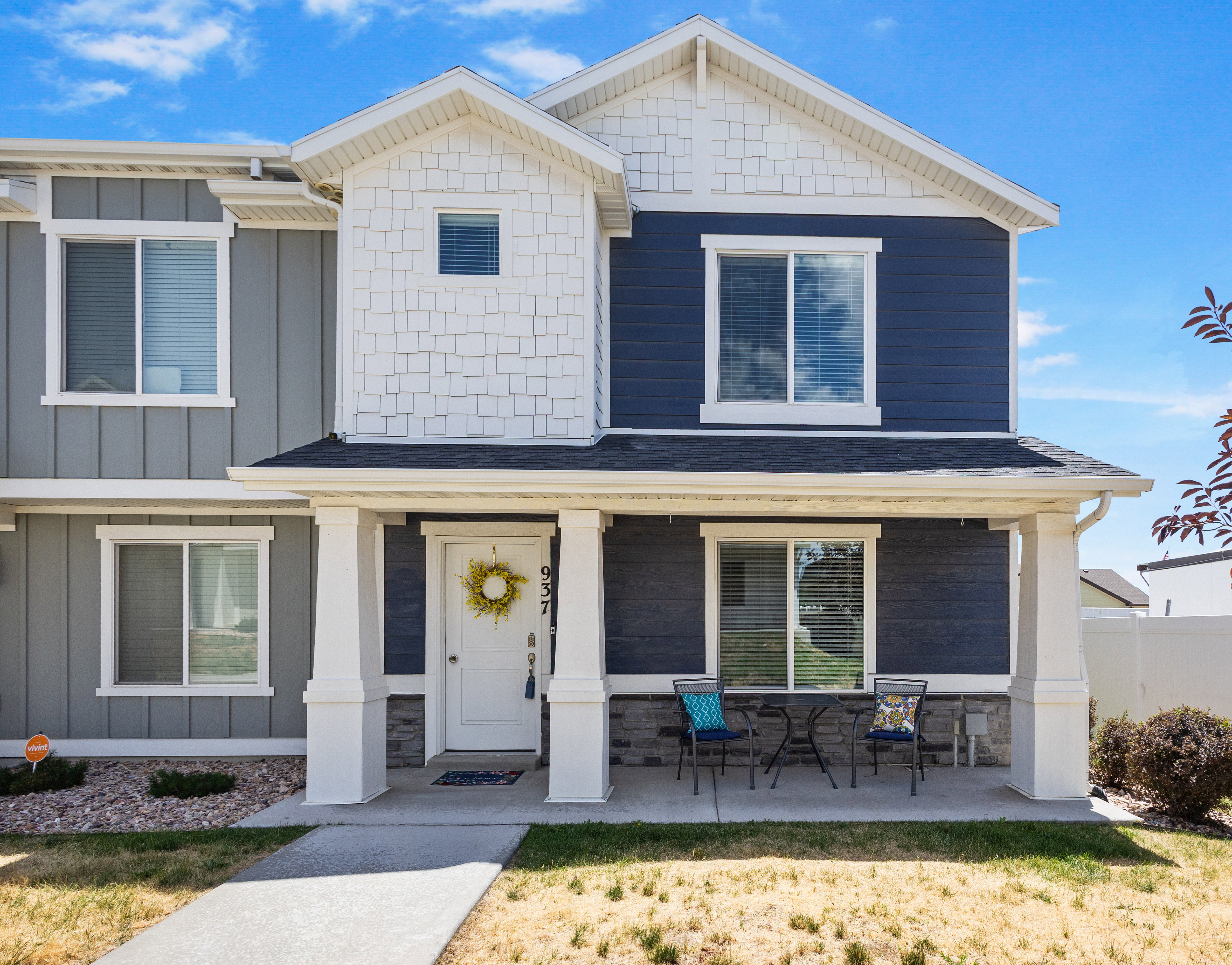Two-story exterior with a covered porch featuring two white columns and dark blue and gray siding