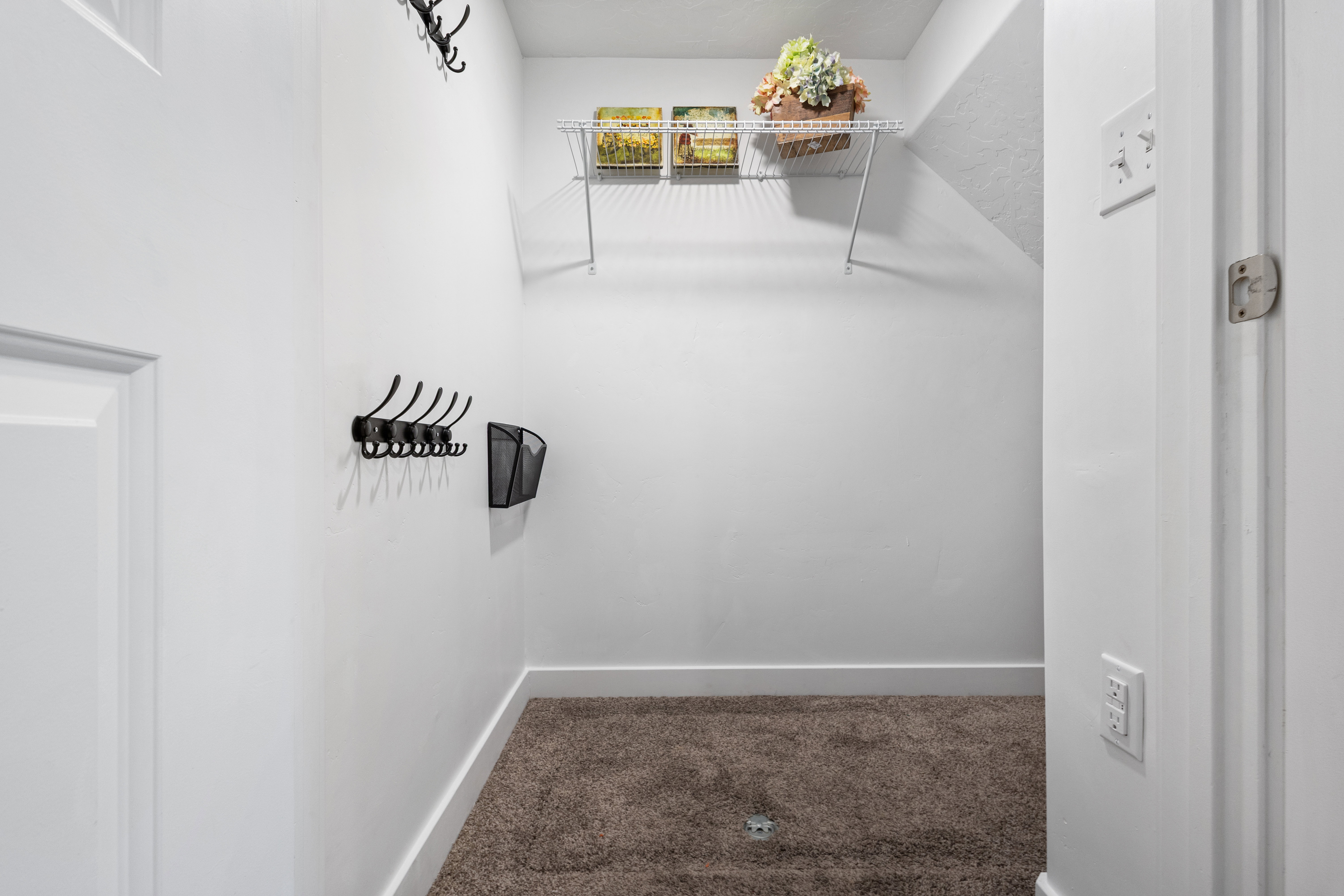 Room under the stair that is utilized as mudroom/drop station