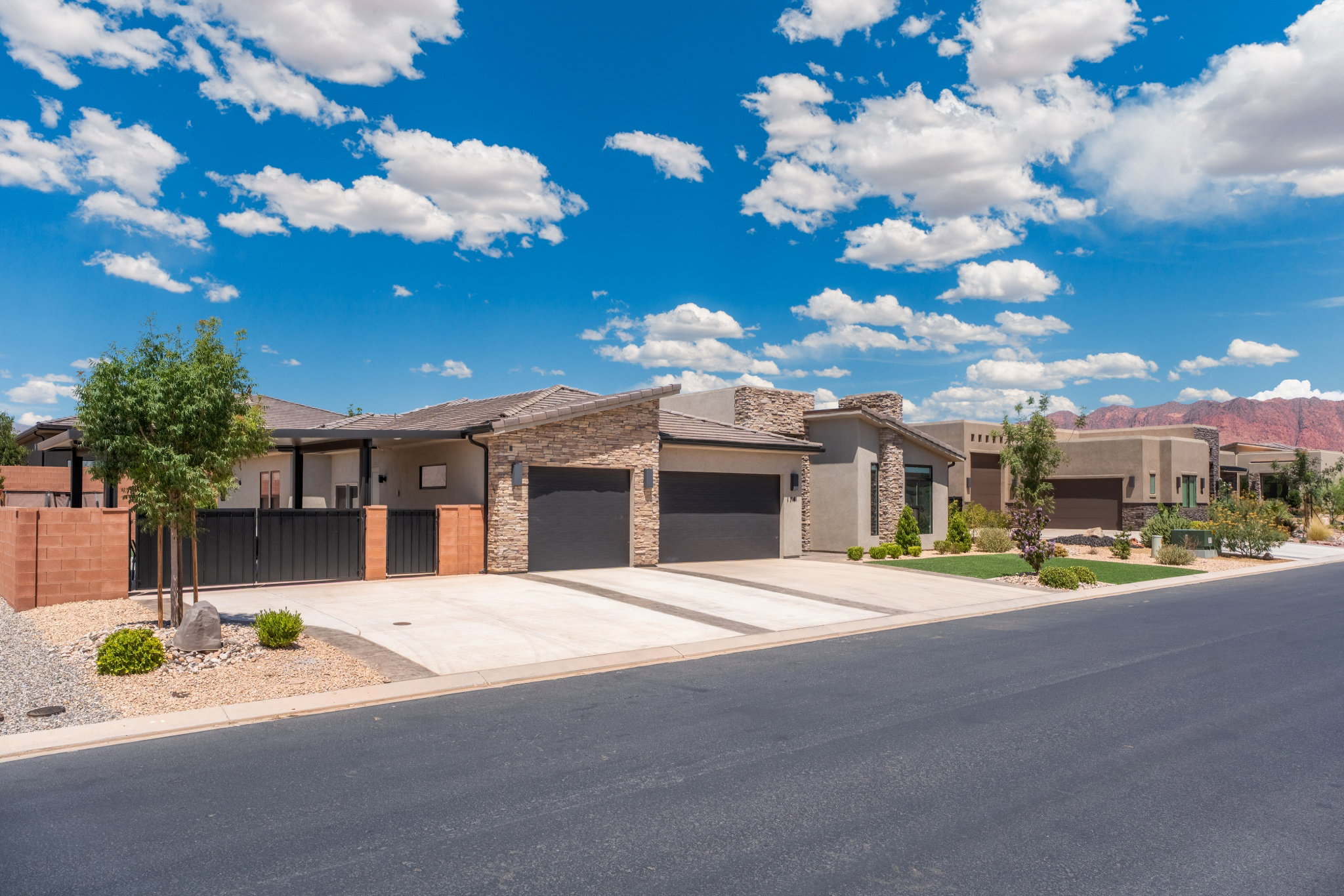 Contemporary-style residence featuring a stone and stucco facade, a two-car garage, and desert-adapted landscaping