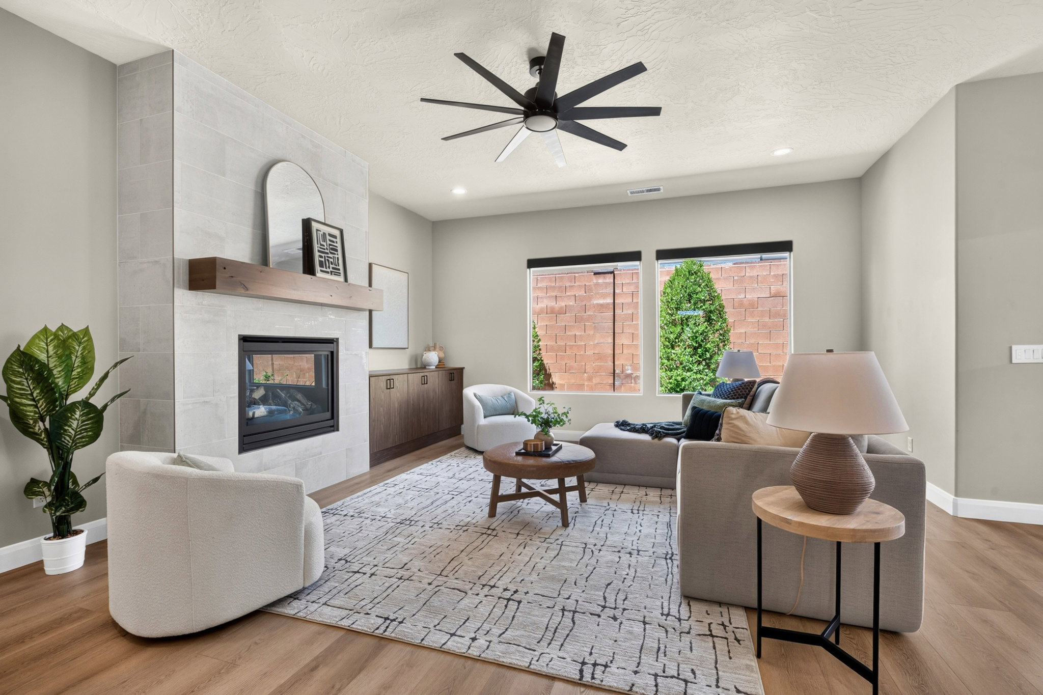 Living area featuring wood-finish flooring, a contemporary fireplace with a wood mantle and tile surround, and built-in cabinetry
