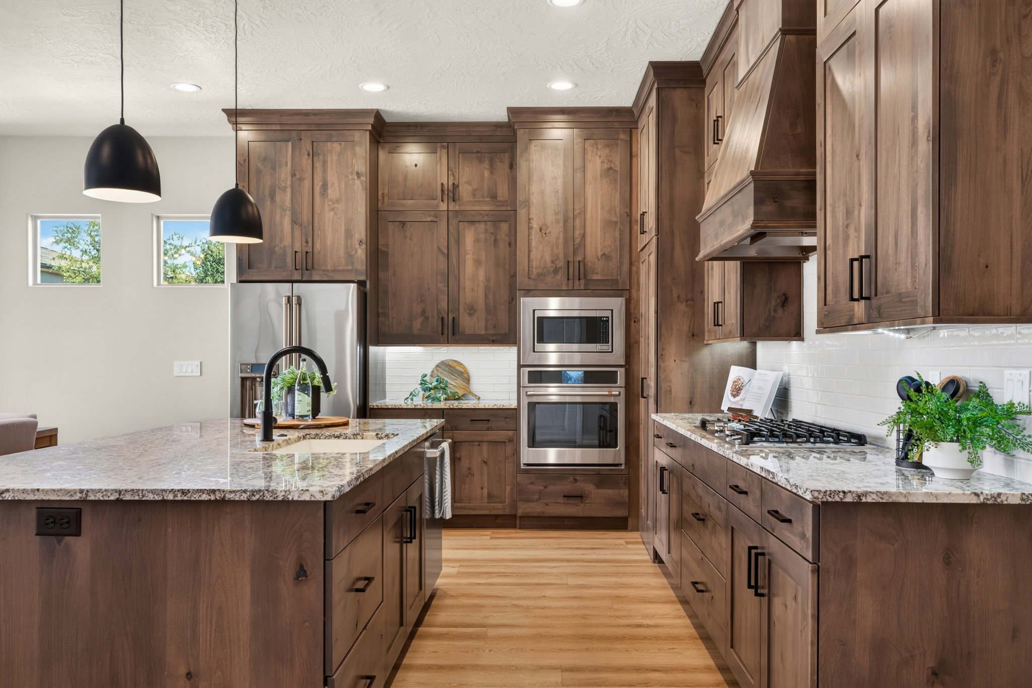 Kitchen featuring wood cabinetry, light-toned granite countertops, stainless steel appliances, and a tile backsplash