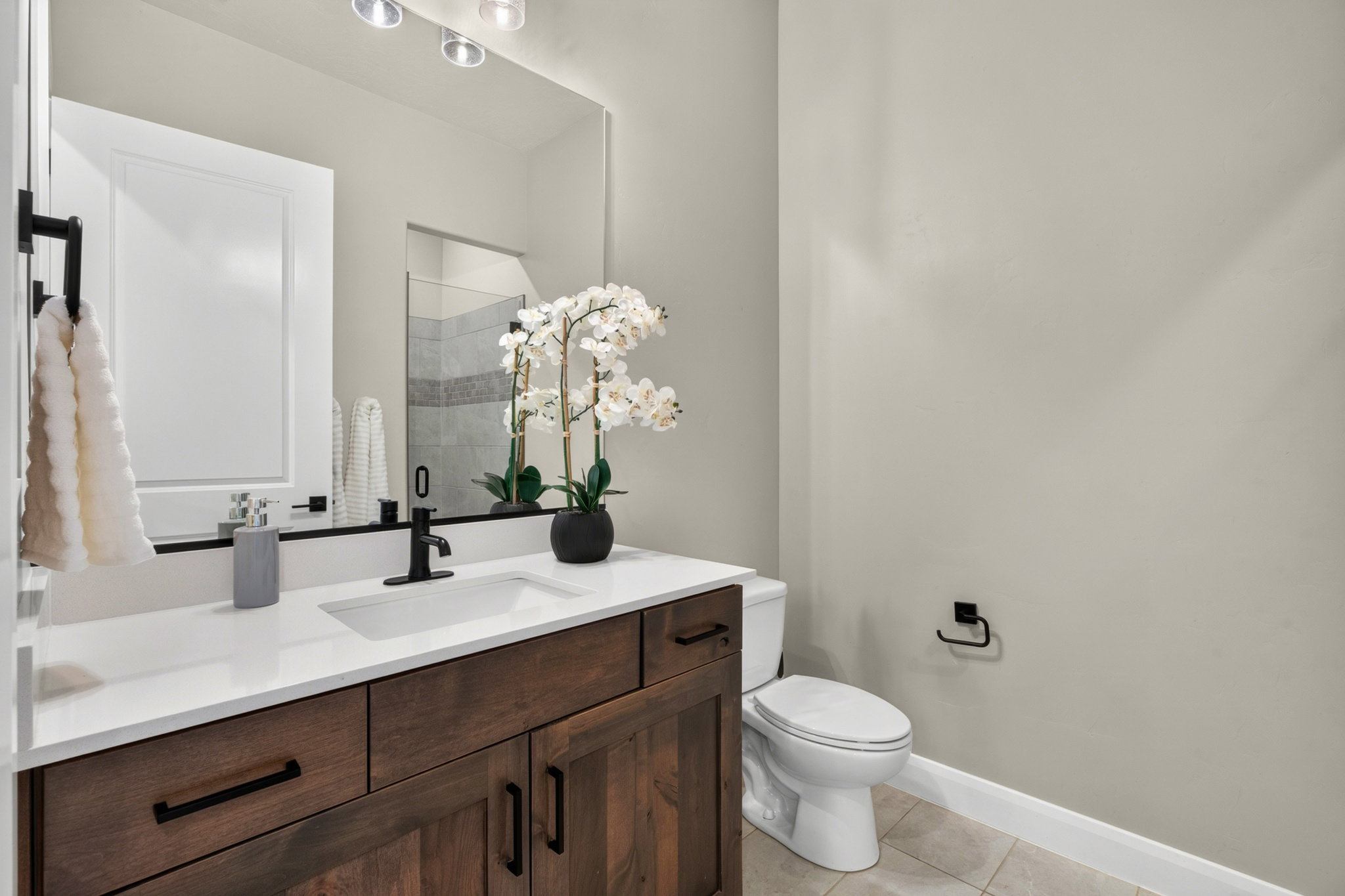 Bathroom vanity with a white countertop and integrated sink, complemented by a matte black faucet