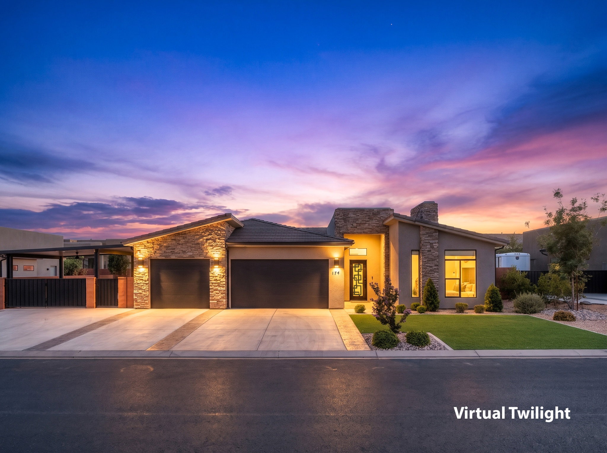 Modern stucco and stone-clad residence featuring a two-car garage, manicured lawn, paved driveway, and covered side patio with a dark privacy fence