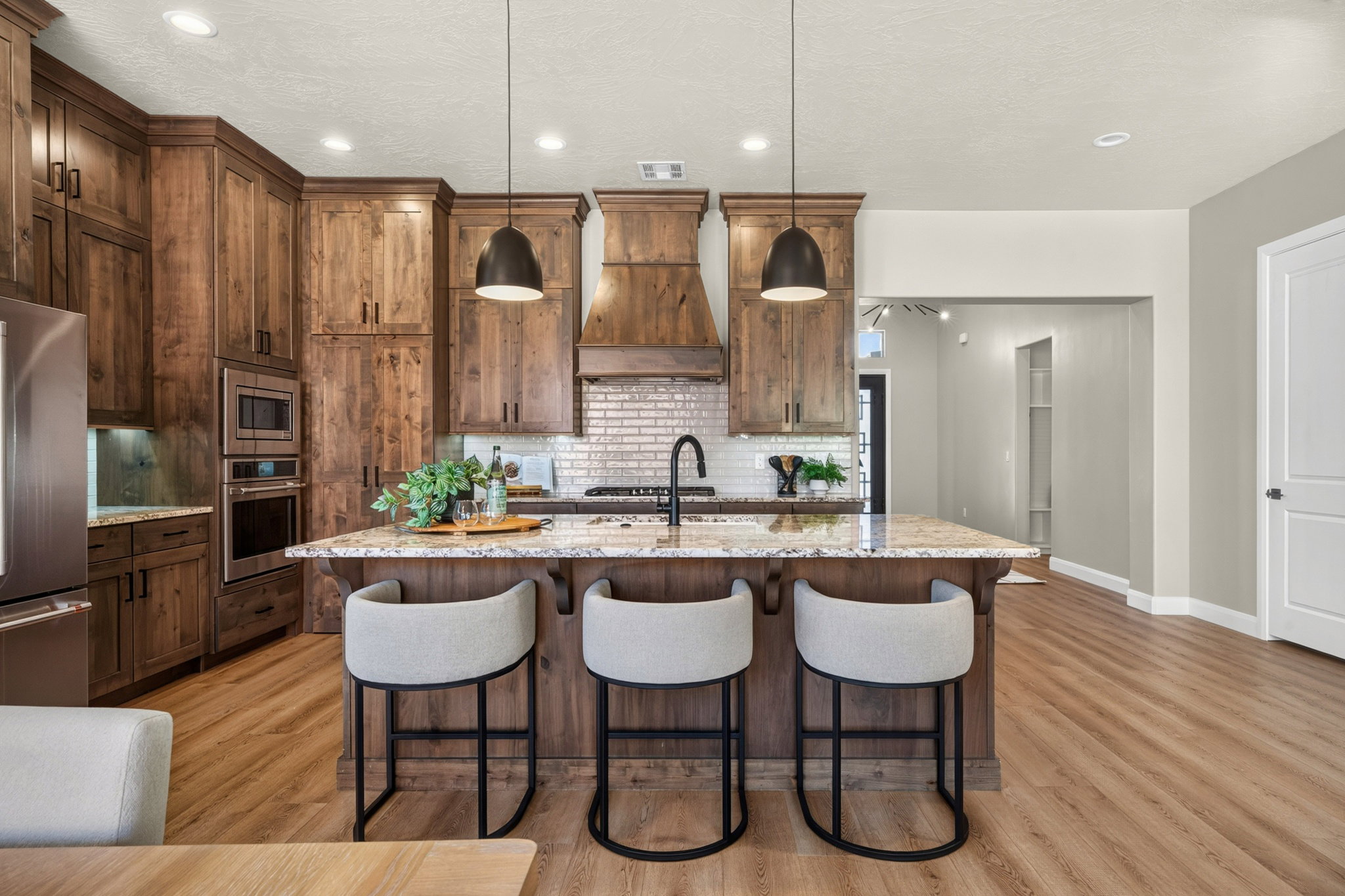 Kitchen featuring a large central island with seating, granite-style countertops, wood-finish flooring, recessed lighting, and stainless steel appliances