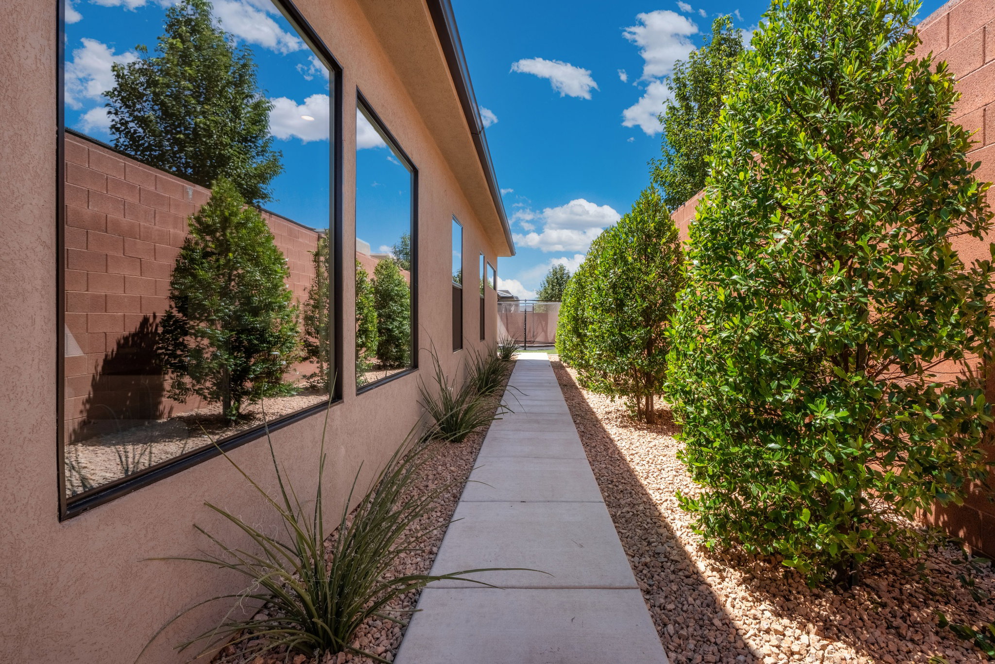 Side yard featuring a concrete pathway, privacy walls, and mature landscaping