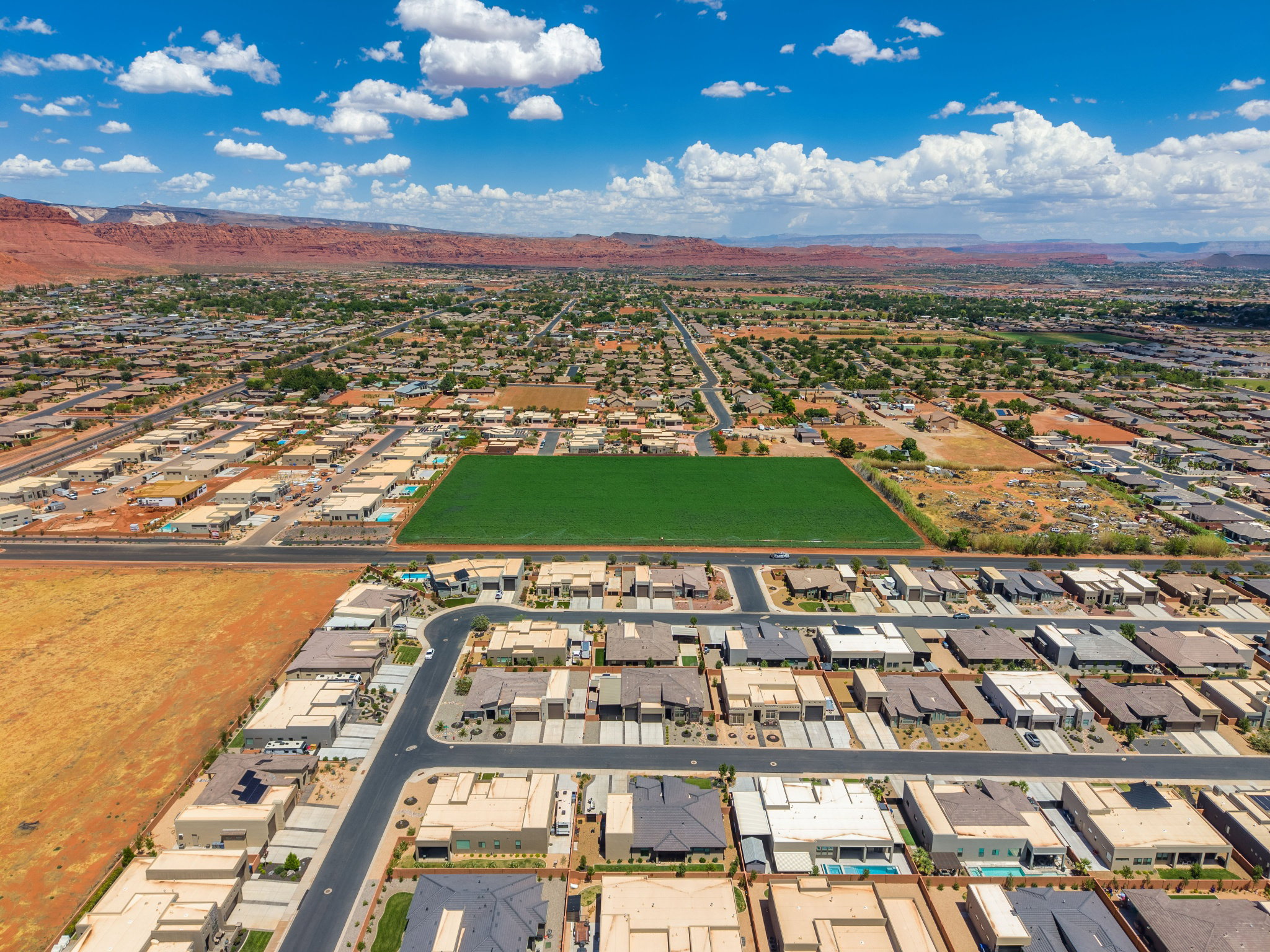 Aerial perspective showcasing a residential development with varied rooflines and a distinctive green field