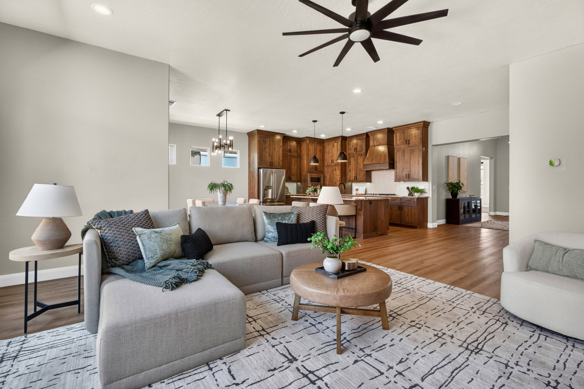Open-concept living space featuring wood-finish flooring, recessed lighting, and a dark-toned ceiling fan