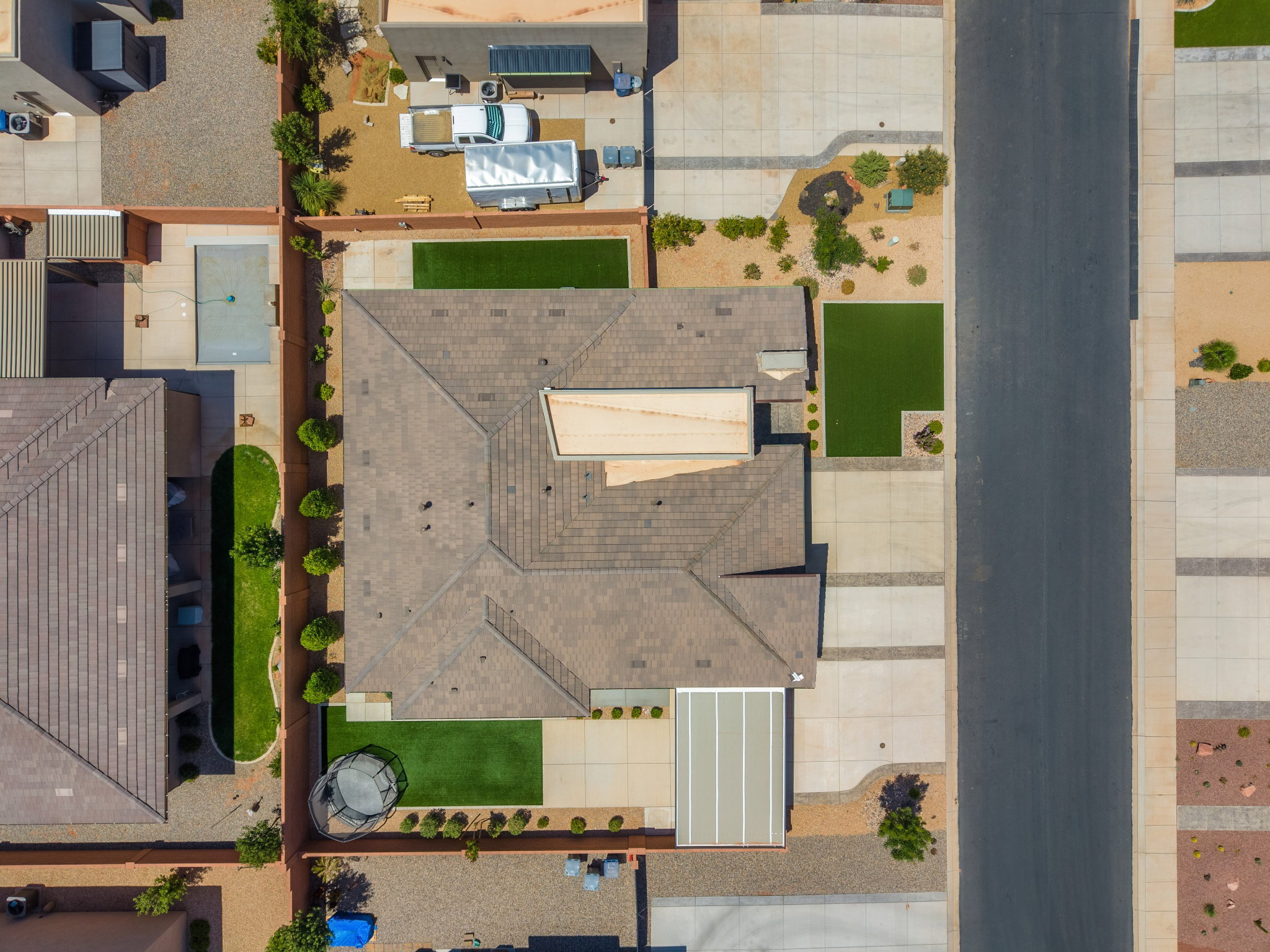 Overhead property showcasing a tiled roof, multiple concrete driveways, and artificial turf sections