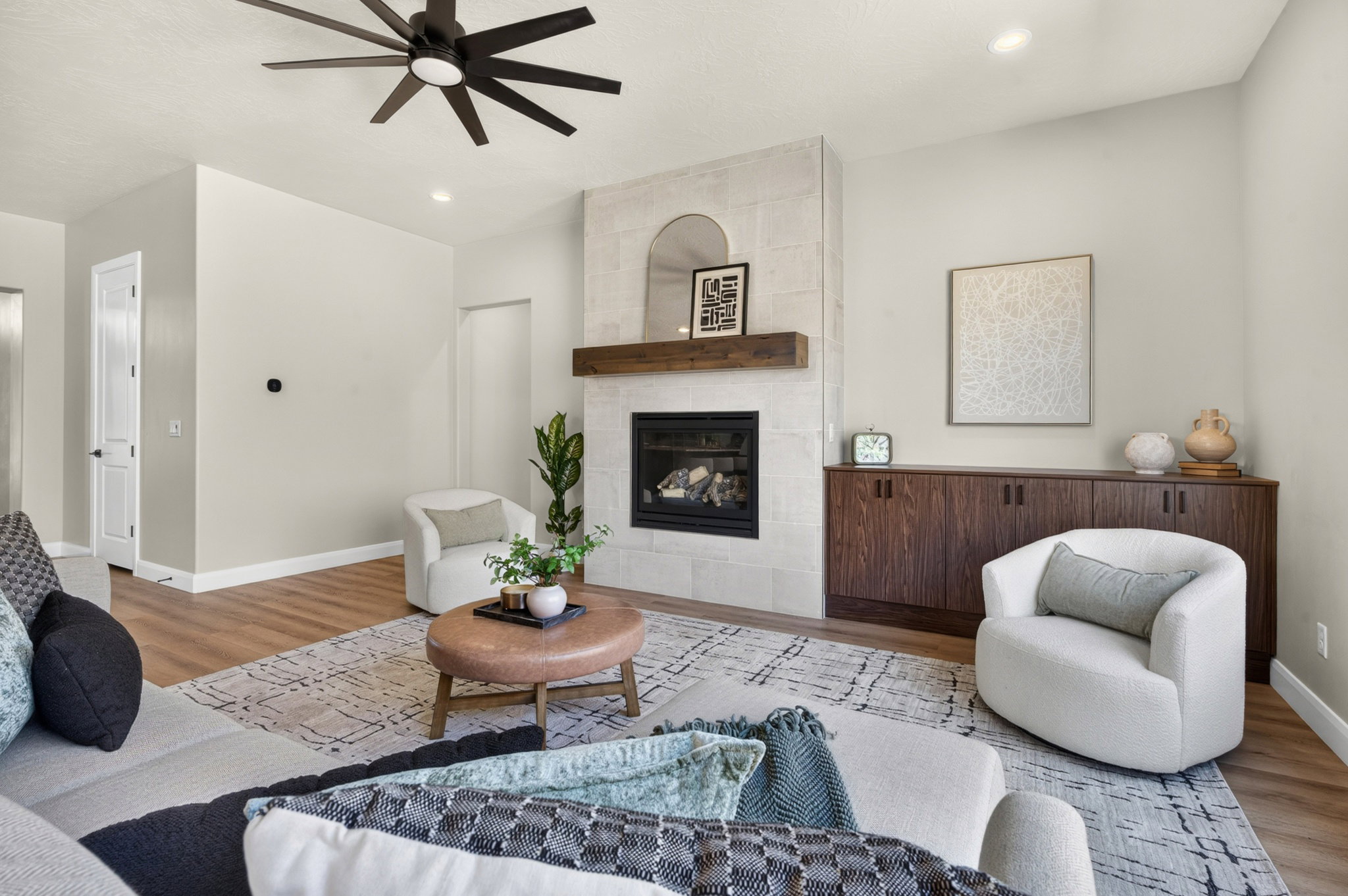 Living space featuring a stone-clad fireplace with a wood mantel, built-in dark wood cabinetry, a contemporary ceiling fan, recessed lighting, and wood-finish flooring