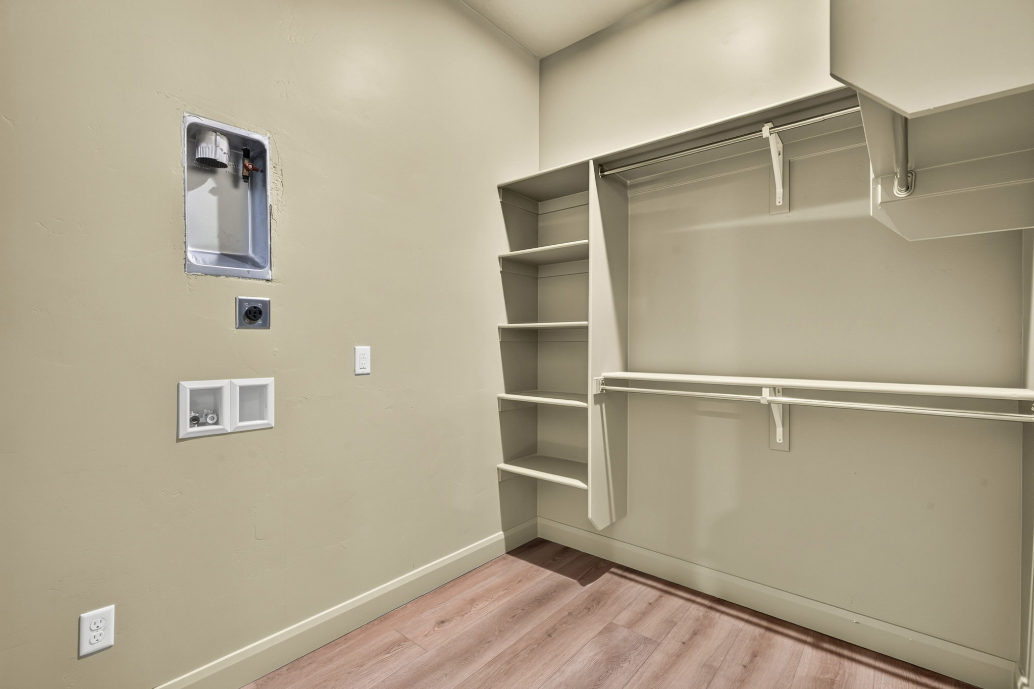 Dedicated laundry area featuring wall connections for appliances, integrated shelving, and dual clothing rods