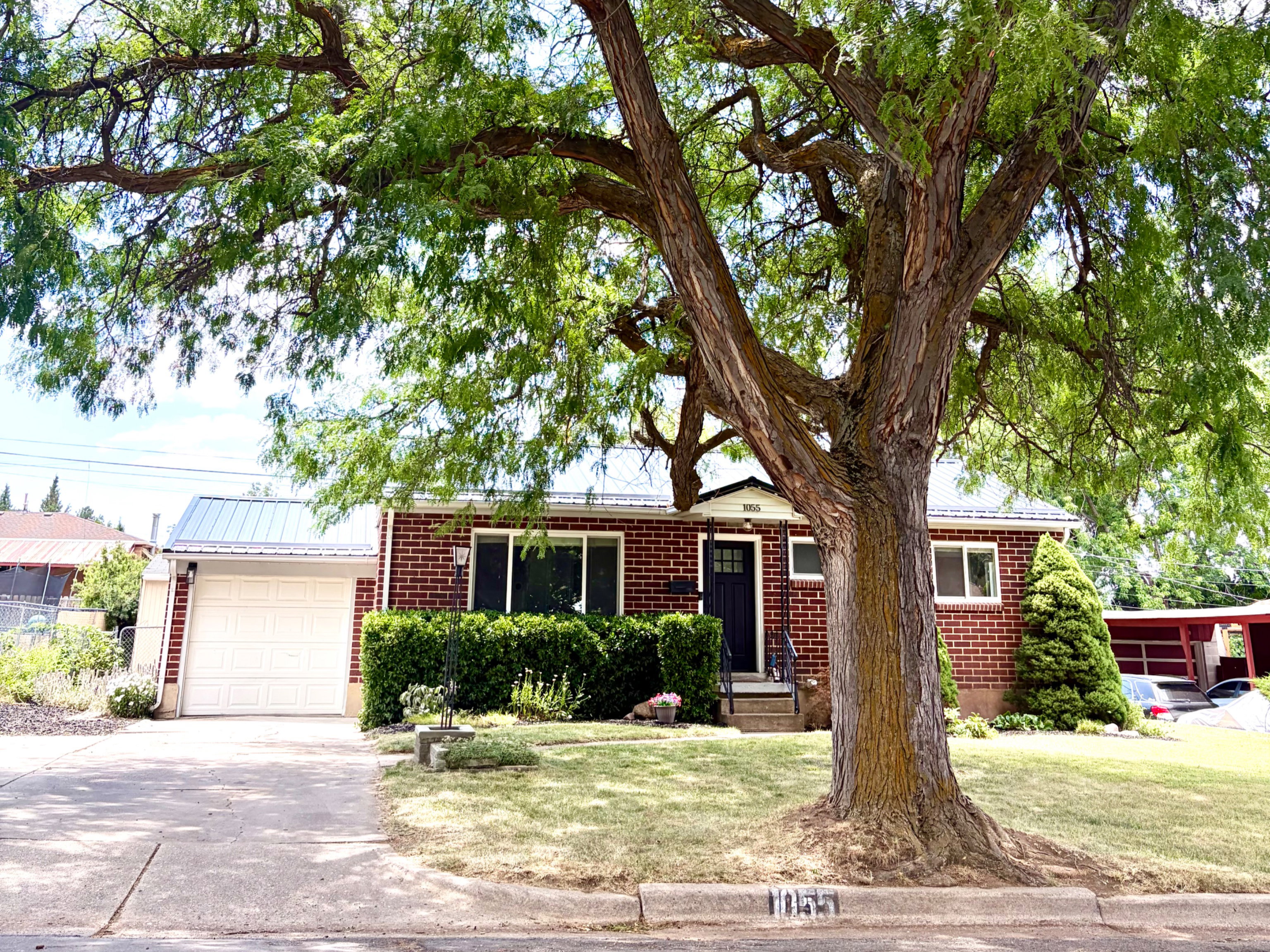 Brick-front residence featuring a metal roof and an attached garage with a white door