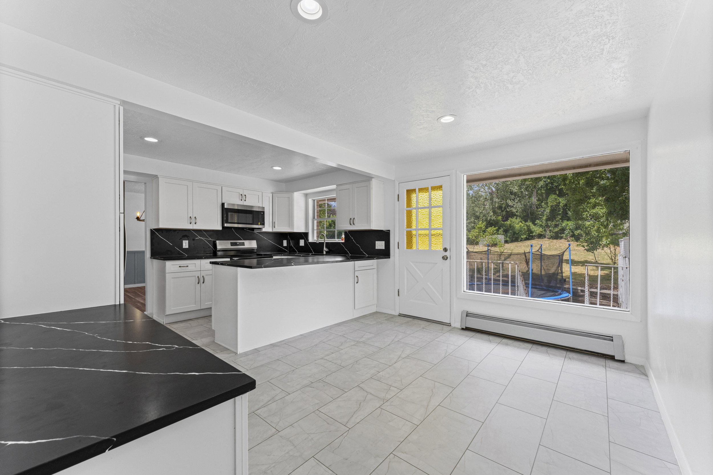 Spacious kitchen with white cabinetry, dark quartz countertops, and a full suite of stainless steel appliances