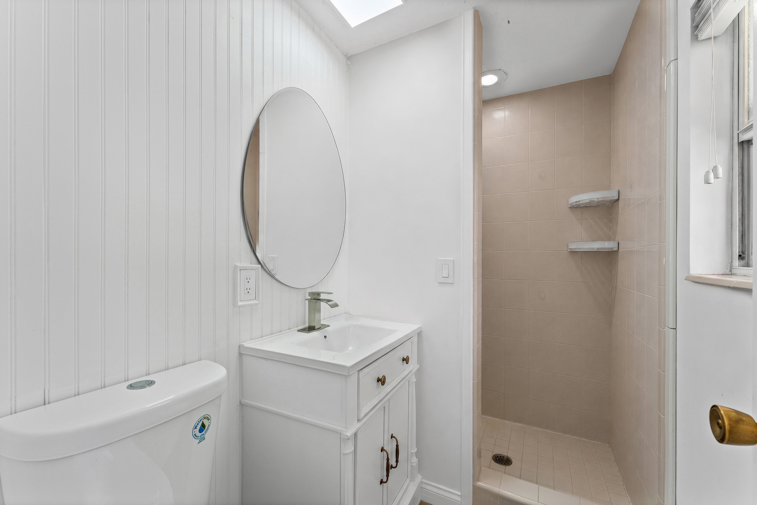 Contemporary bathroom featuring a white vanity with a rectangular sink, brushed nickel faucet, and an oval mirror