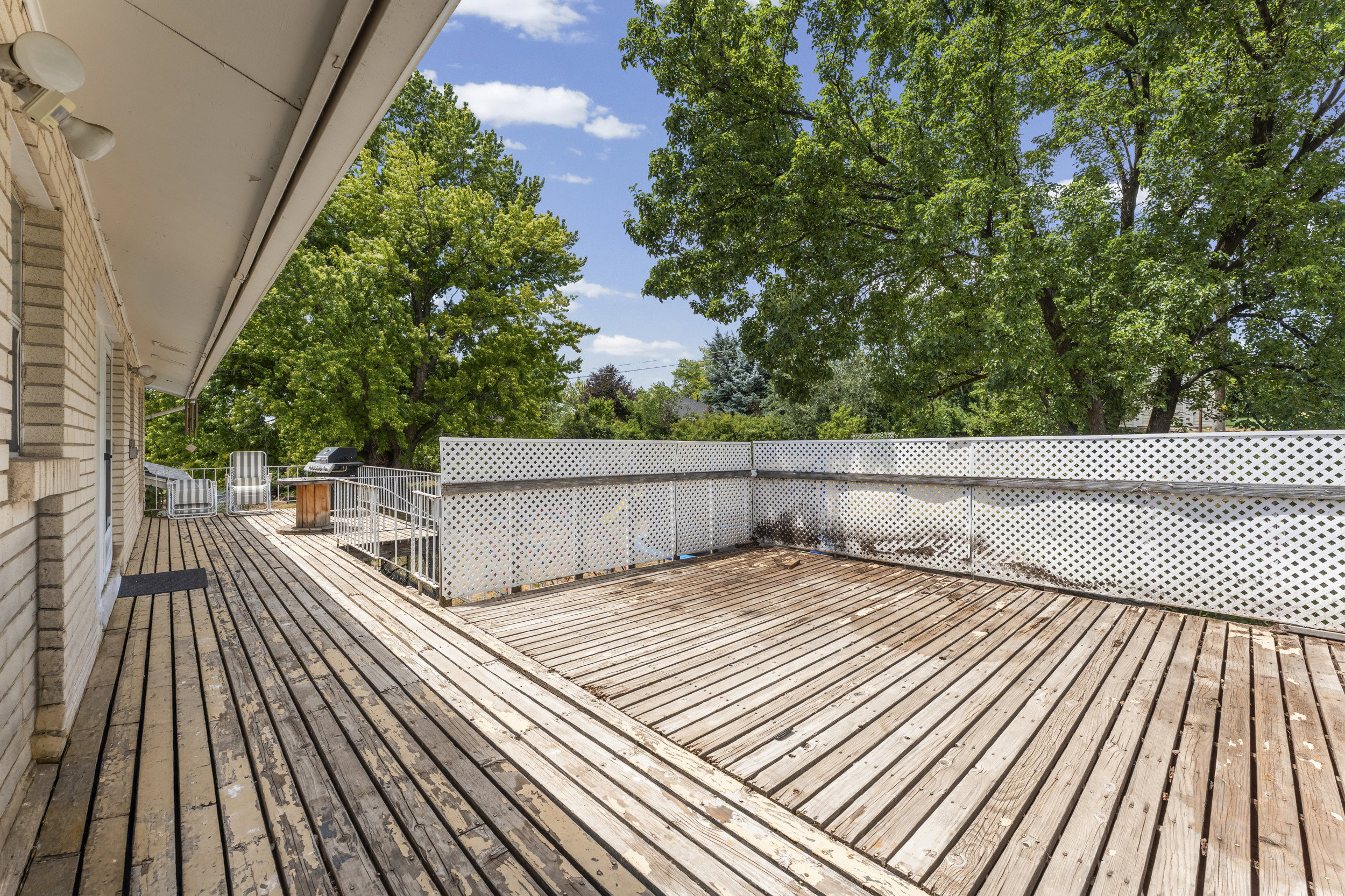 Expansive outdoor deck featuring wood plank flooring and white lattice fencing