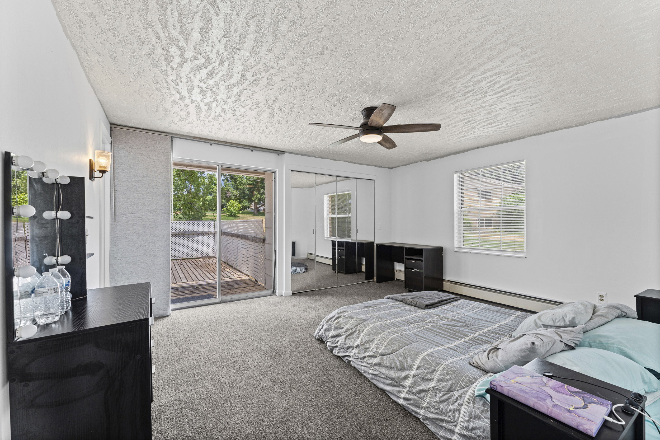 Room featuring a sliding glass door to an outdoor deck, a single window, ceiling fan with integrated lighting, and mirrored closet doors