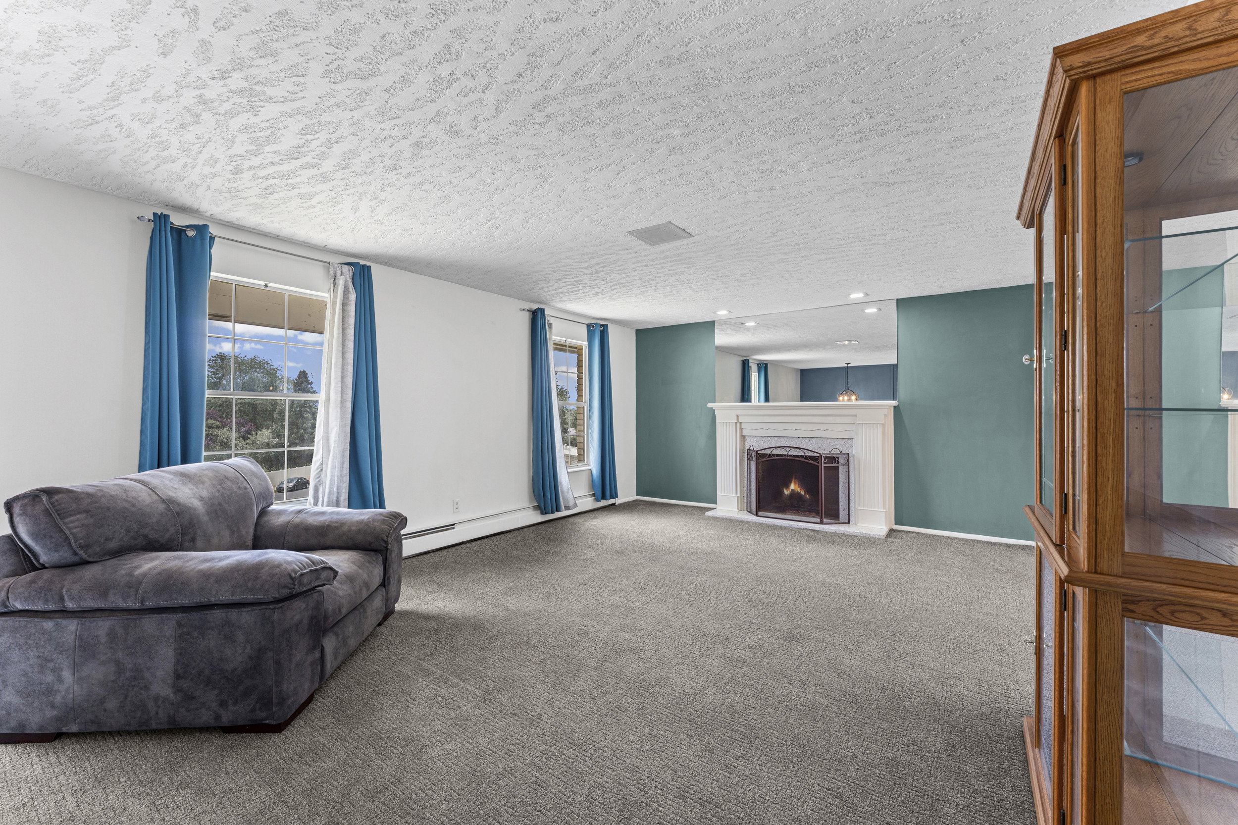 Living area featuring a white fireplace with a dark metal screen, flanked by teal accent walls