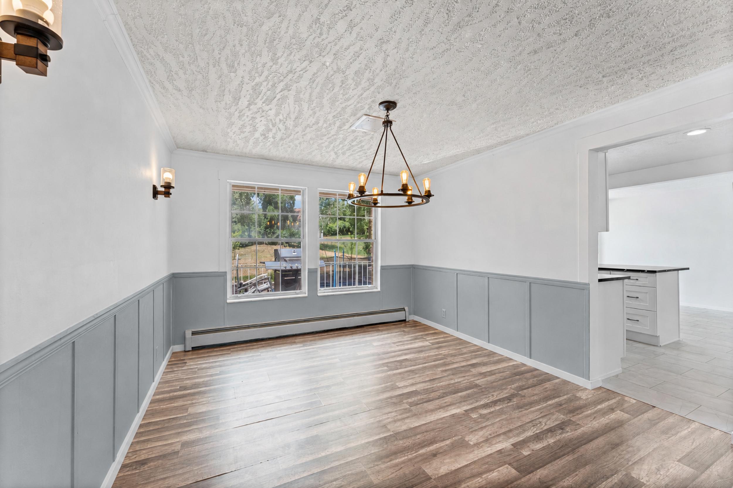 Dining area featuring wood-finish flooring, two large windows, and an overhead chandelier