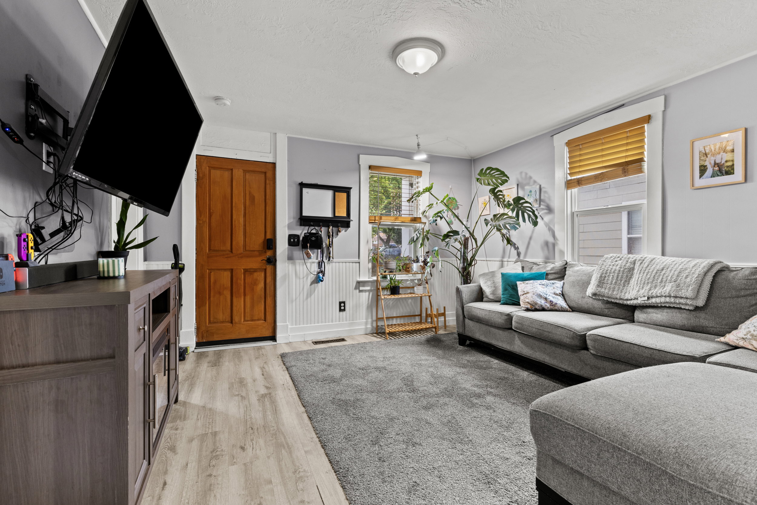 Living area with light wood-finish flooring, a paneled entry door, and wainscoting details