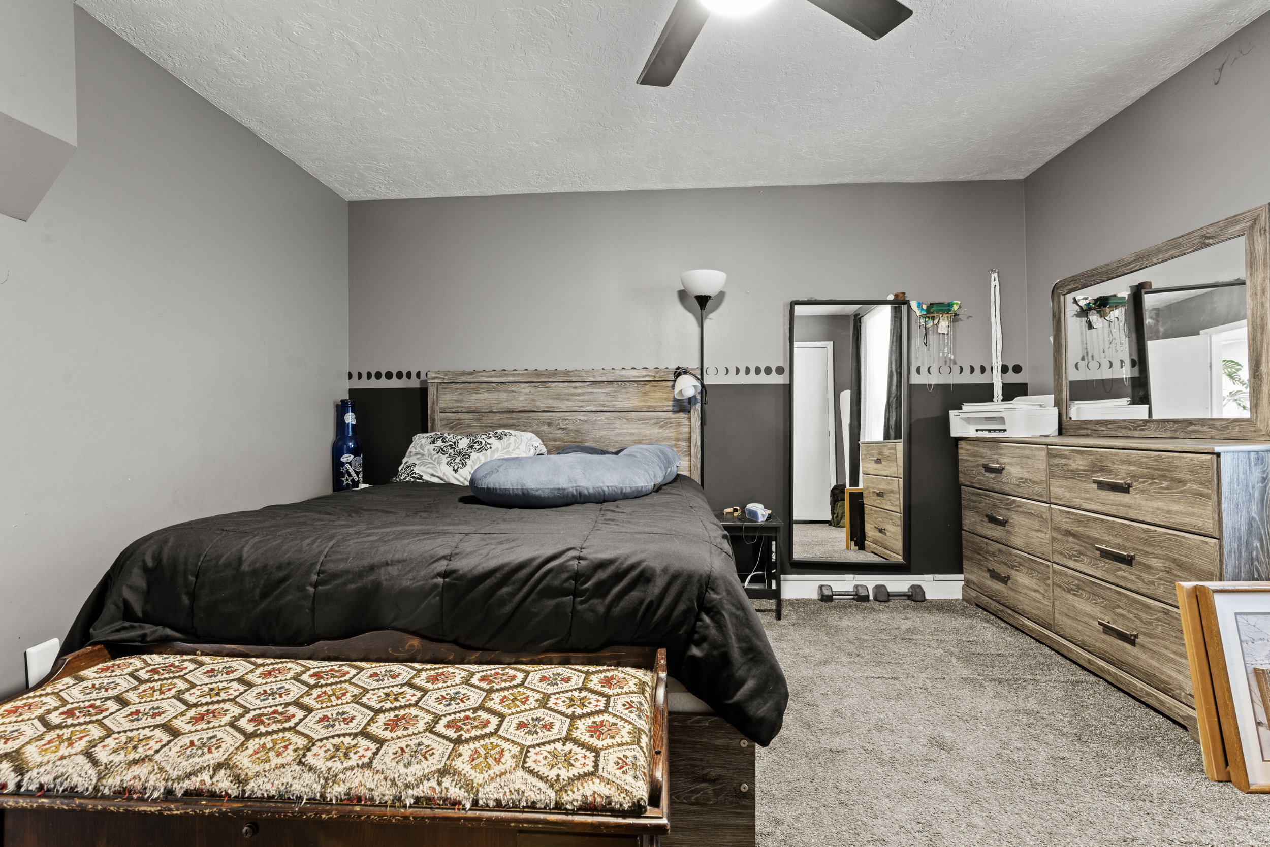 Bedroom featuring a wood-finish headboard, gray carpeting, and a ceiling fan