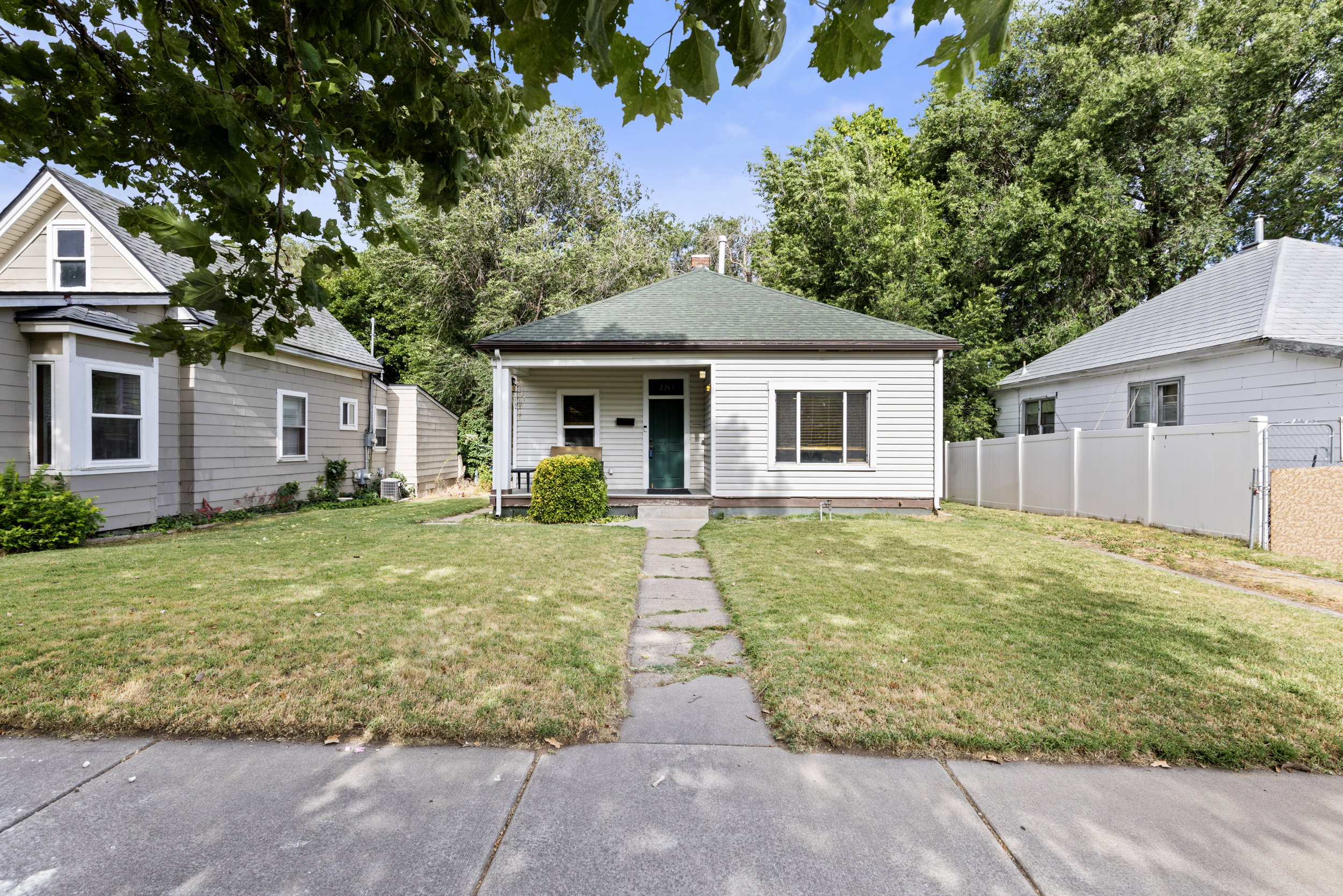 Single-story home featuring horizontal siding, a green roof, and a front porch with a dark green door