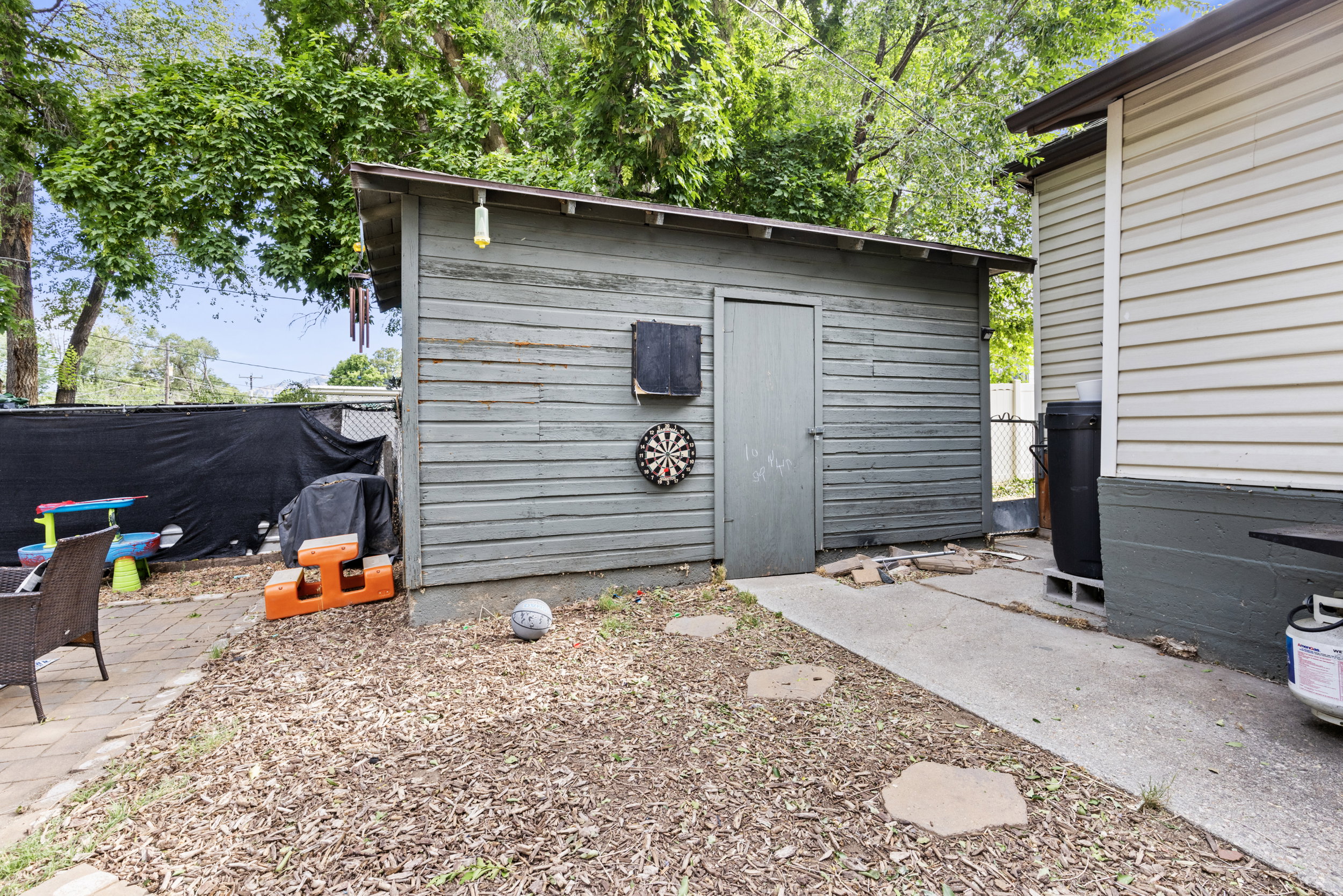 Detached shed with horizontal wood siding, asphalt shingle roof, and a single entry door
