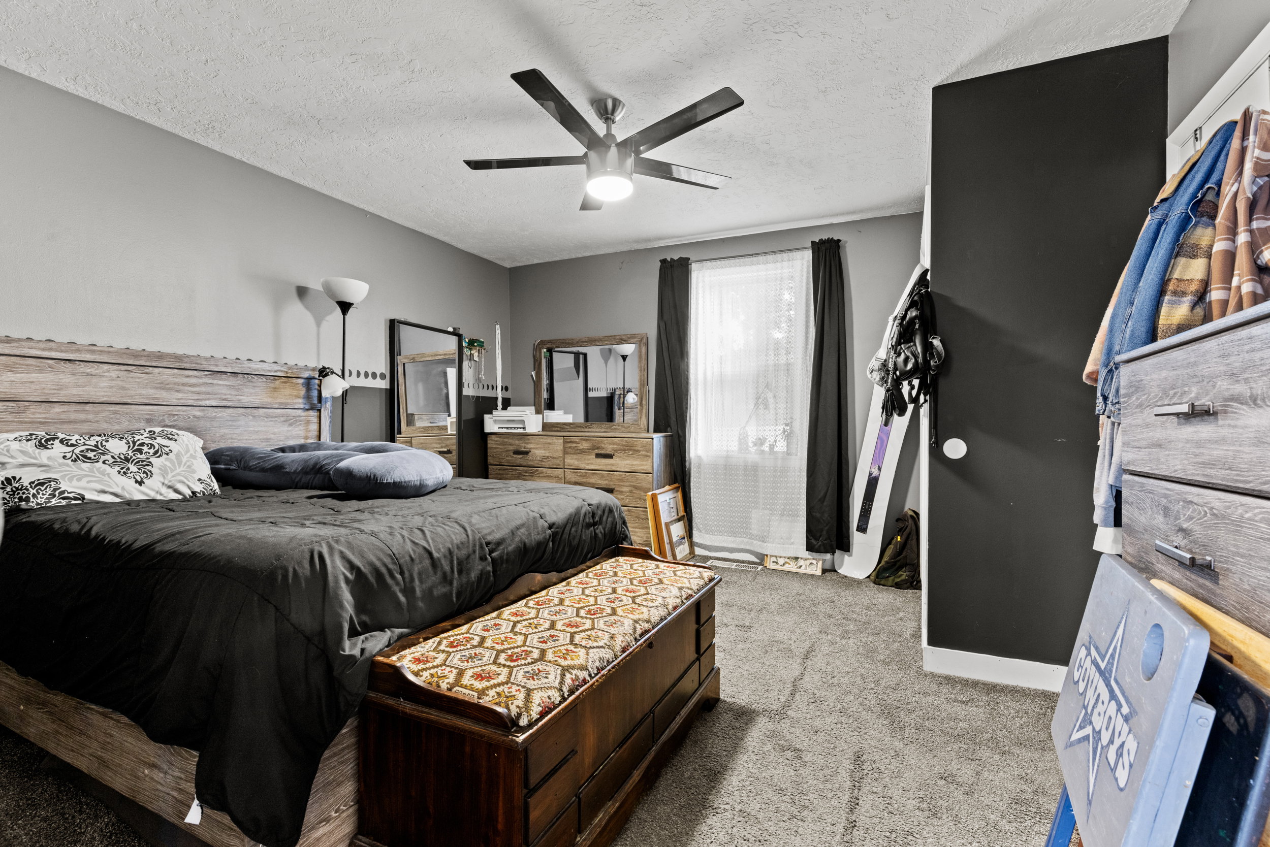 Carpeted room featuring a ceiling fan with integrated lighting, a window with curtains and blinds, and a built-in closet with a dark door