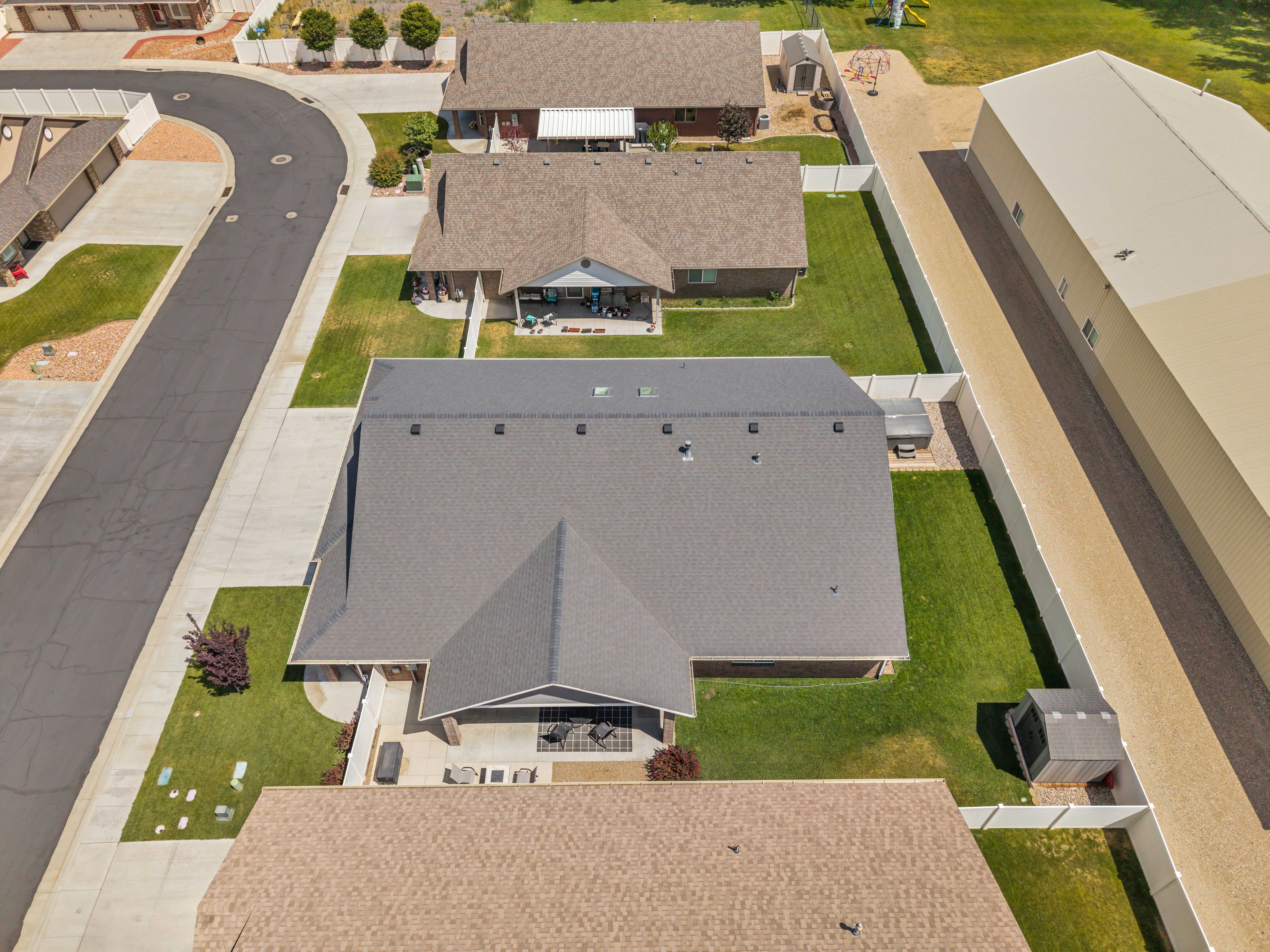 Expansive property featuring a grey shingled roof, manicured lawn, and a paved driveway