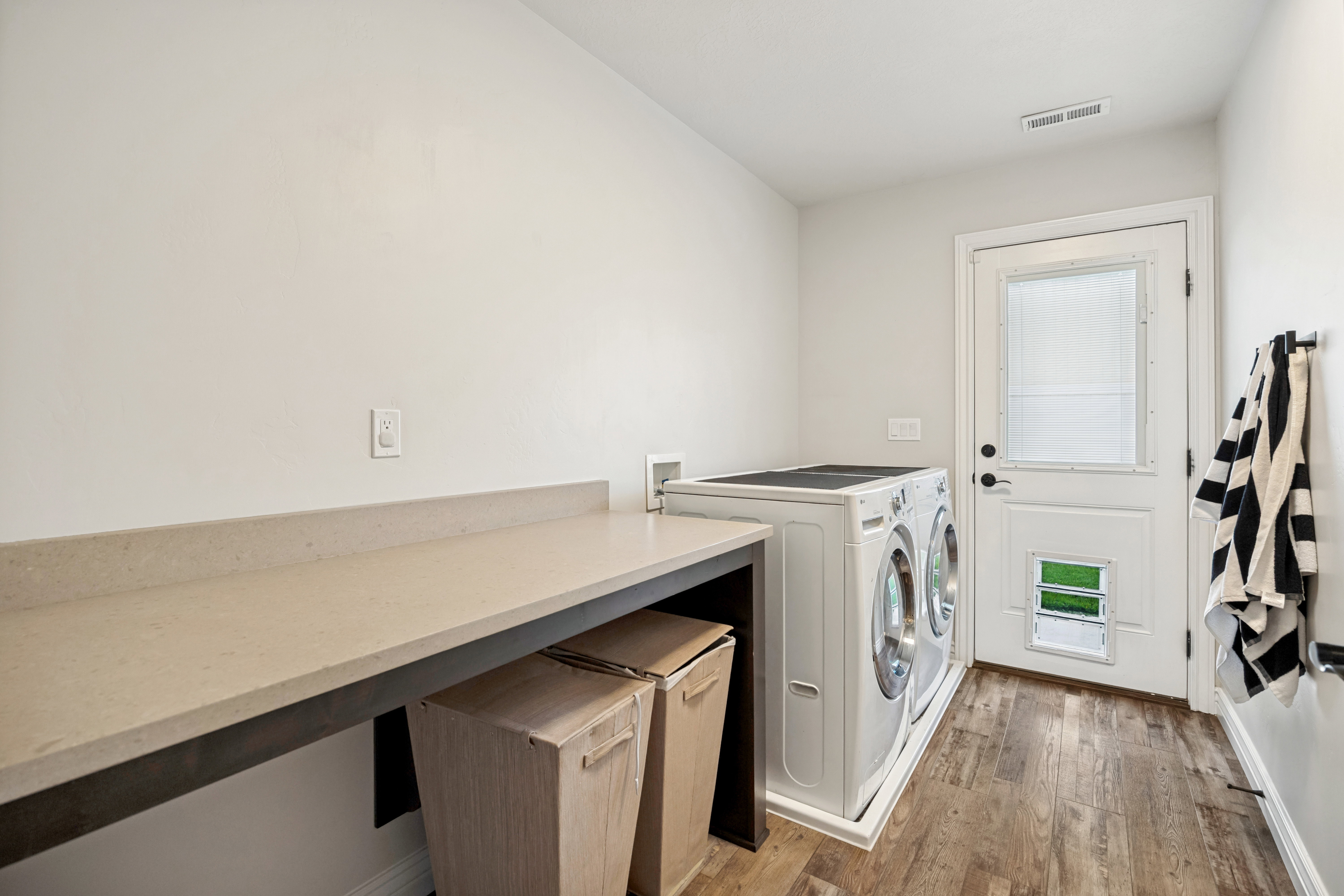 Dedicated laundry area featuring wood-finish flooring and a stone-finish countertop