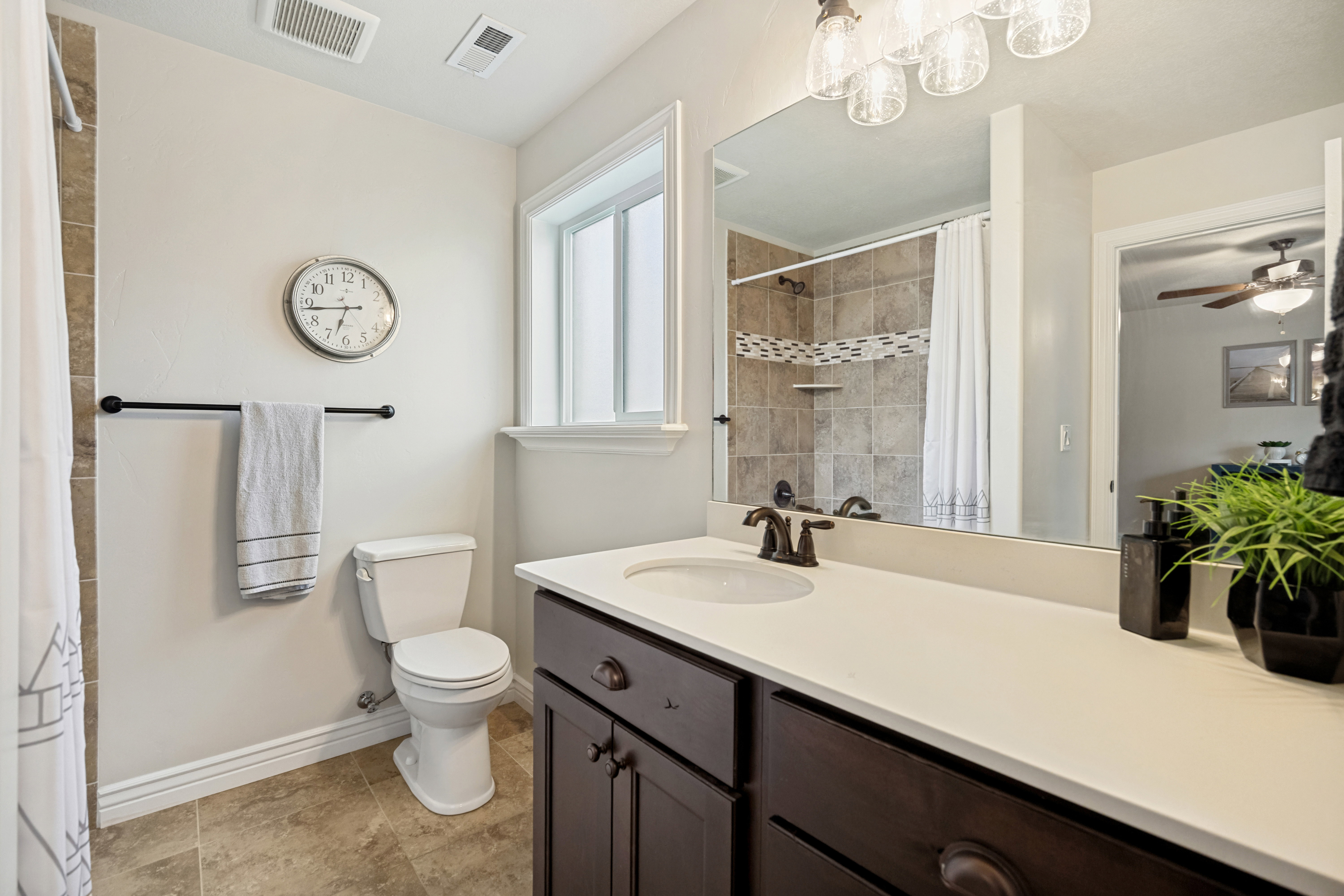 Bathroom featuring a dark wood-finish vanity with a light-colored countertop, an undermount sink, and a framed mirror