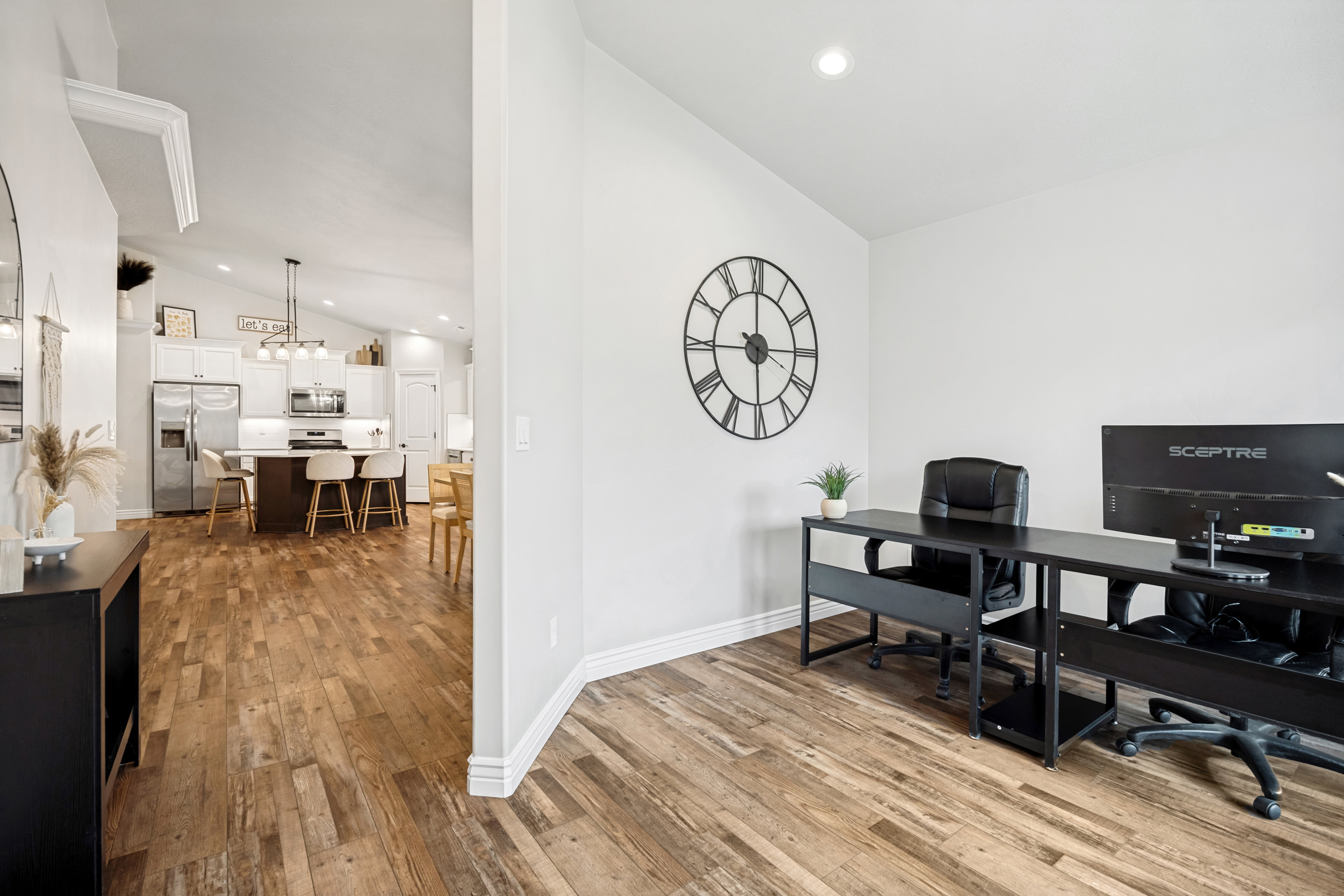 Office space featuring wood-finish flooring, white baseboards, and bright overhead lighting