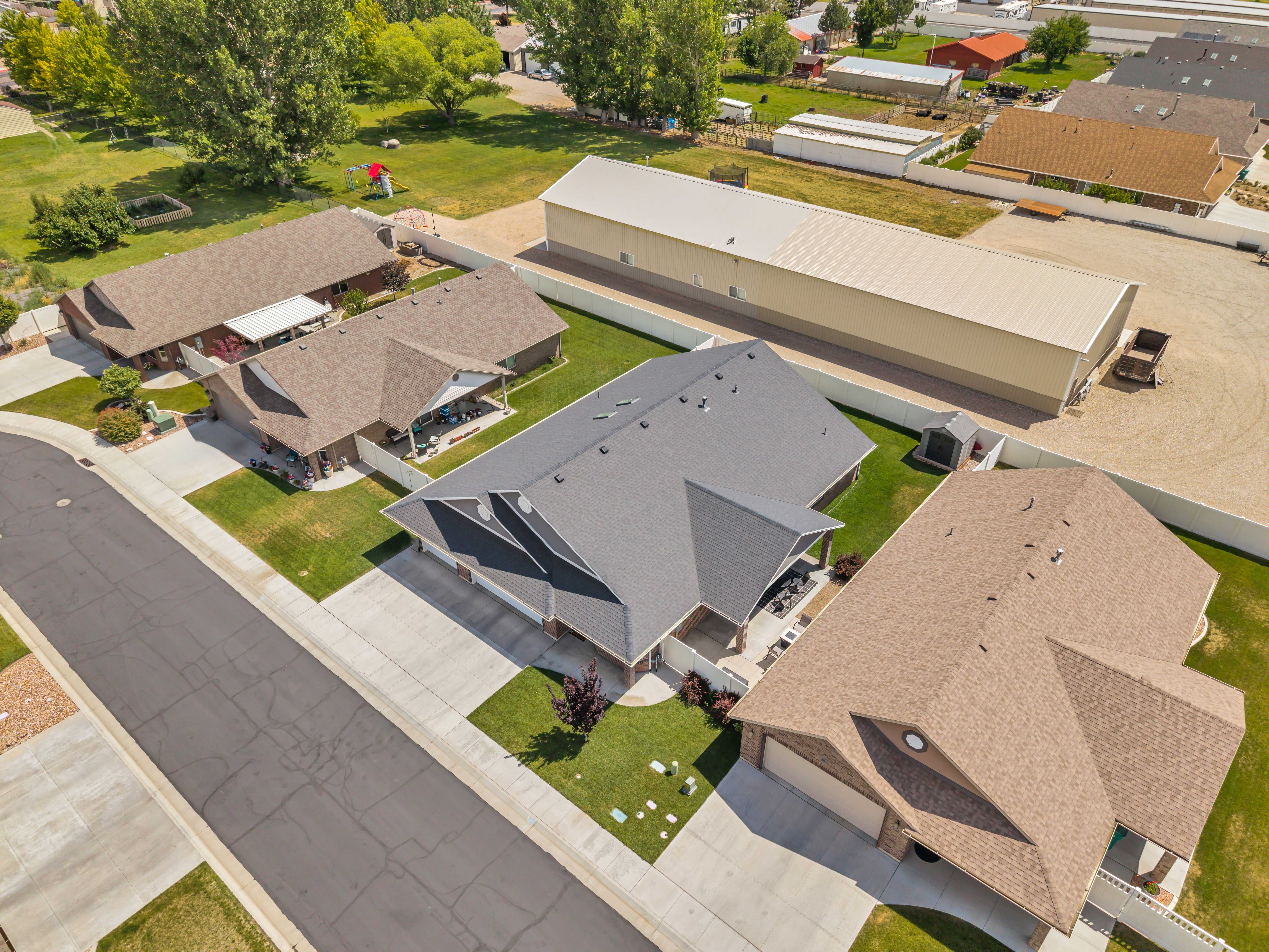 Aerial perspective highlighting the property's expansive lot with a large, well-maintained structure featuring a light-colored metal roof